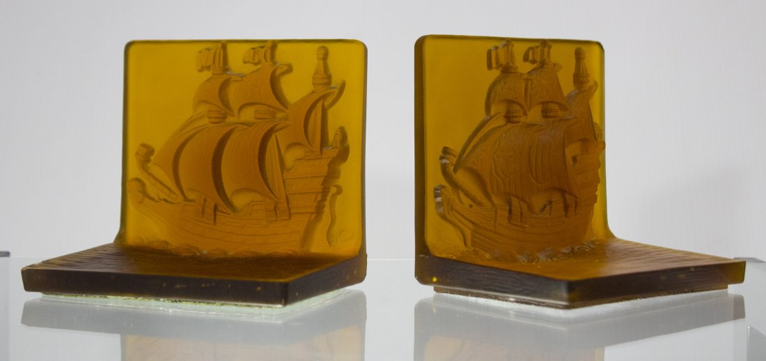 AMBER INTAGLIO GLASS GALLEON BOOKENDS - UNIQUE ITEM: AMBER INTAGLIO GLASS GALLEON BOOKENDS - UNIQUE ITEM.Never seen these before. Good condition showing chip in corner of one bookend in picturesSize: 5.5 h, 6w