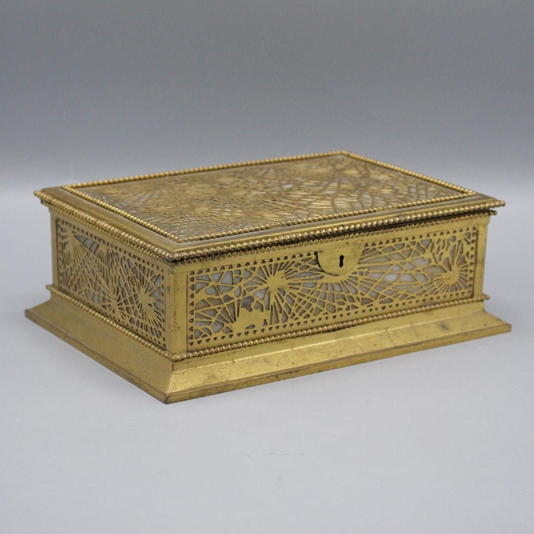 TIFFANY STUDIOS New York Dore Pine Needle Jewelry Box: Tiffany Studios New York # 830 Gold Dore Pine Needle jewelry Box with caramel slag glass panels, fitted jewelry interior. With key. Marked and numbered on bottom: Tiffany Studios New York 830. Size: 3