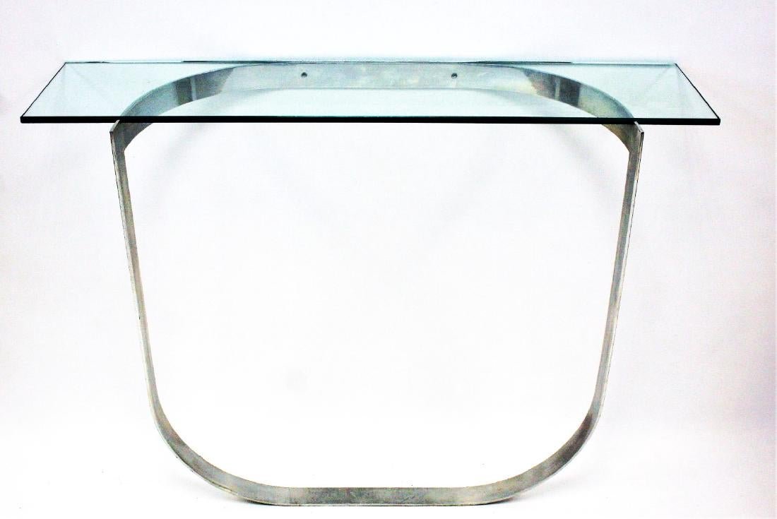 Mid-Century Polished Aluminum Curved Flat Bar Stand: Mid-Century Polished Aluminum Curved Flat Bar Hall Stand with glass top. Stand is half round, attaches to wall. Note: glass has a chip on inside edge, See Picture. Style of Milo Baughman. Size: 33 in.
