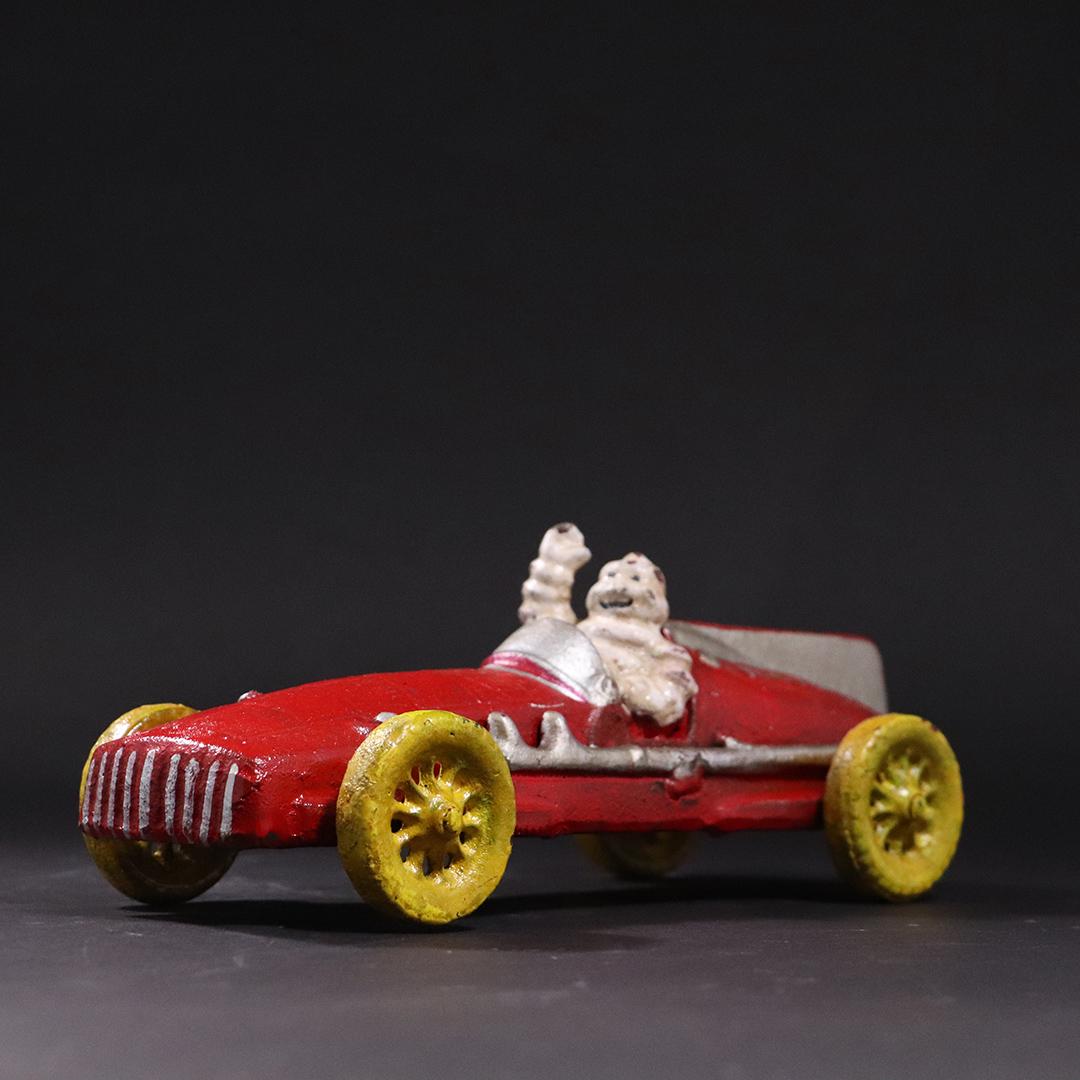 Michelin Man Cast Iron Figure in Red Race Car - Hubley: Michelin Man Cast Iron Figure in Red Race Car - Hubley embossed underside. size: 3.5h x 10L x 3.75w