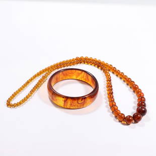 Amber Glass Beads Necklace and Amber Lucite Bangle: Amber Glass Beads Necklace and Amber Lucite Bangle. Size: necklace 26 in. length, 5/8 in. largest bead [graduated sizes] ; bangle 2.75 in. x 3/4 in.