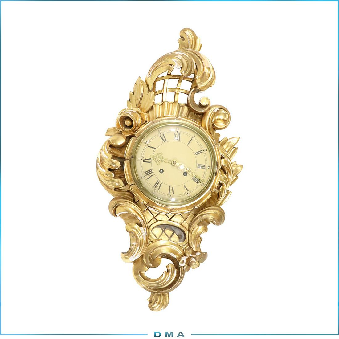 Exacta Hasselblad Sweden Carved Gold Gilt Cartel Clock: Exacta Hasselblad Sweden Carved Gold Gilt Cartel Clock. Hand carved wood with flowers, brass backing, brass works. size: 26 in. Length x 14 in. wide