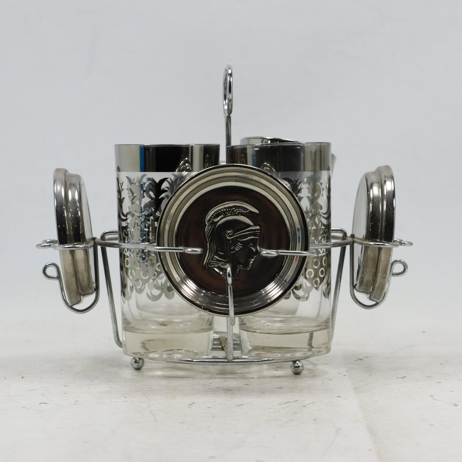 [4] KNIGHT Motife Silvertone Drinking Glasses with Coasters on a Chrome Caddy: [4] KNIGHT Motife Silvertone Drinking Glasses with Coasters on a Chrome Caddy. size: x4 plates .75h 3.75w x4 cups 5.75h 3.75w holder 8.25h 10.25w