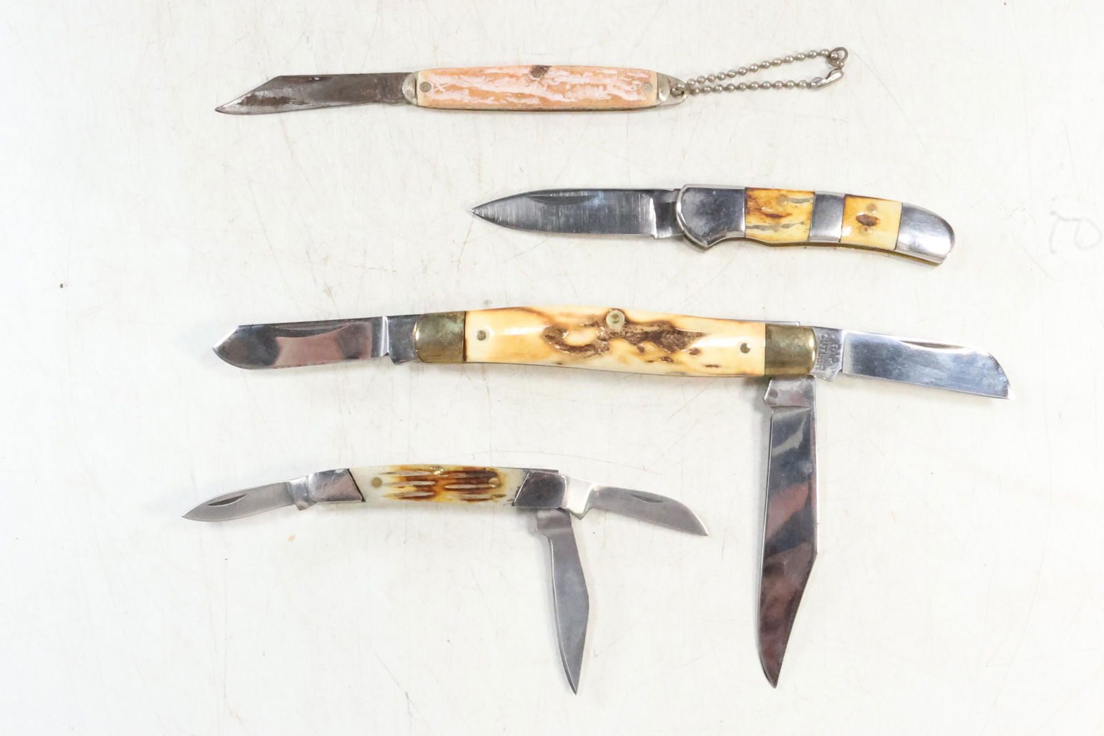 [4] Assorted Pocket Knives: Rap Cutter, Bone & Brass, Bone & Stainless, Prov. Cut. Co. RI USA: [4] Assorted Pocket Knives: Rap Cutter 4 in. x 5/8 in. , Bone & Brass 2 1/2 in. x 3/8 in. , Bone & Stainless 2 3/4 in. x 3/4 in. , Prov. Cut. Co. RI USA 3 in. x 1/2 in.