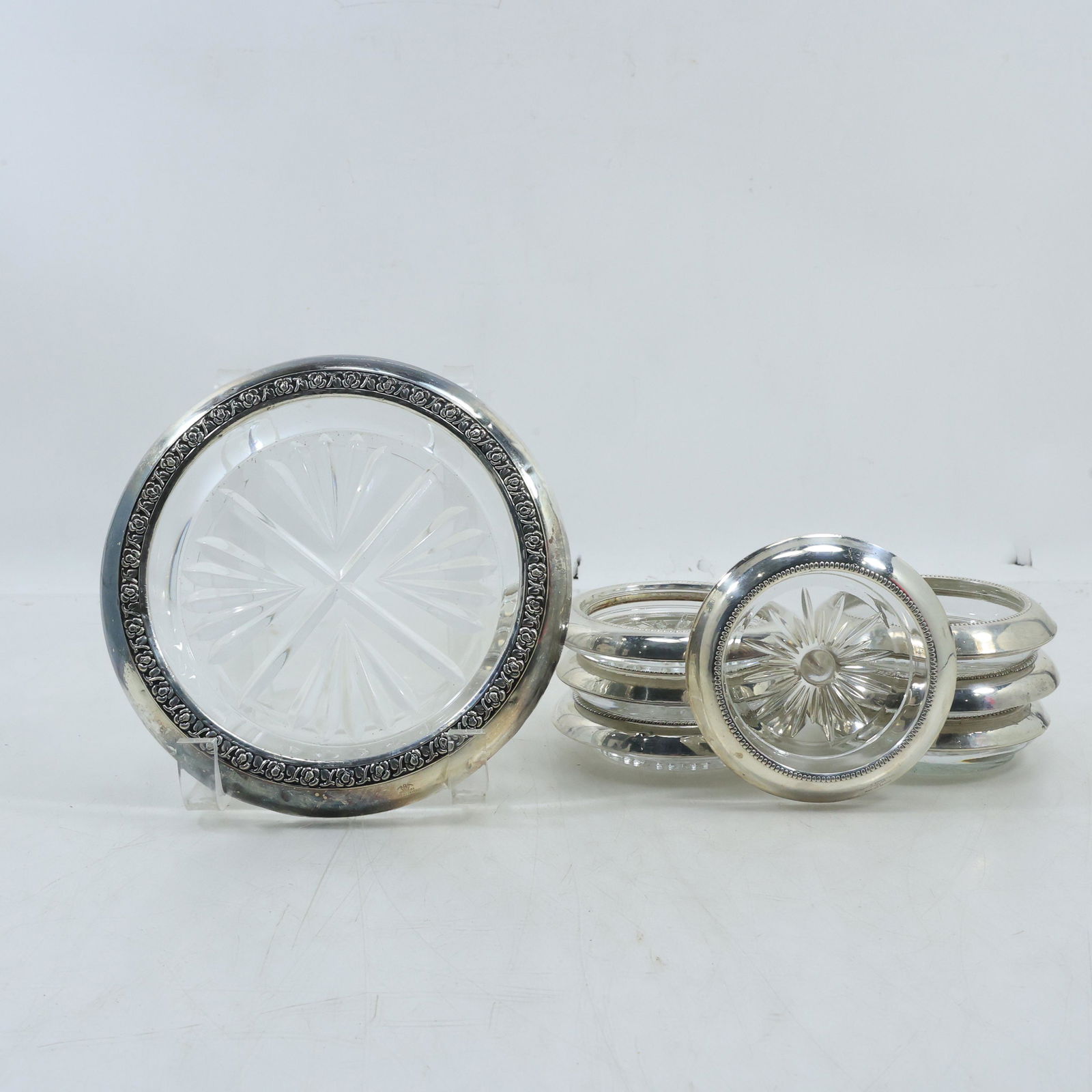 7 Pieces: 6 Cut Glass and Sterling Silver Rim Coasters & Cut Glass and Sterling Wine Bottle Coaster: 7 Pieces: 6 Cut Glass and Sterling Silver Rim Coasters 3 3/4 in. x 1 in. & Cut Glass and Sterling Wine Bottle Coaster 6 3/4 in. x 1 1/2 in. .