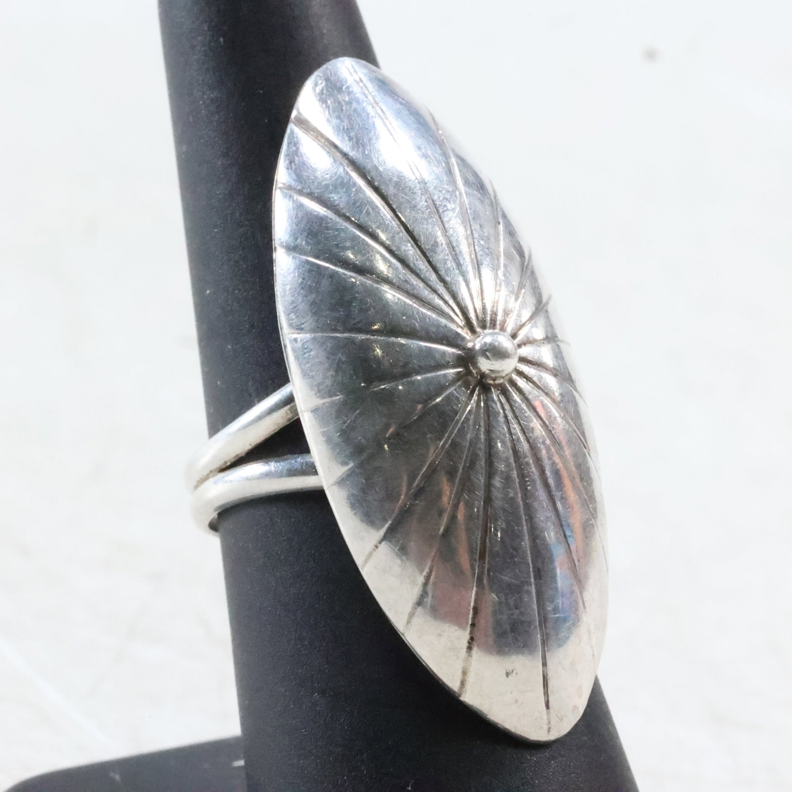 Native American Indian Elongated Oval Shaped Sterling Silver Ring with Unknown Hallmark: Size: 7, 1 3/4"x3/4"Native American Indian Elongated Oval Shaped Sterling Silver Ring with Unknown Hallmark. The front face of this ring showcases a button in the center with a ray design around it. M