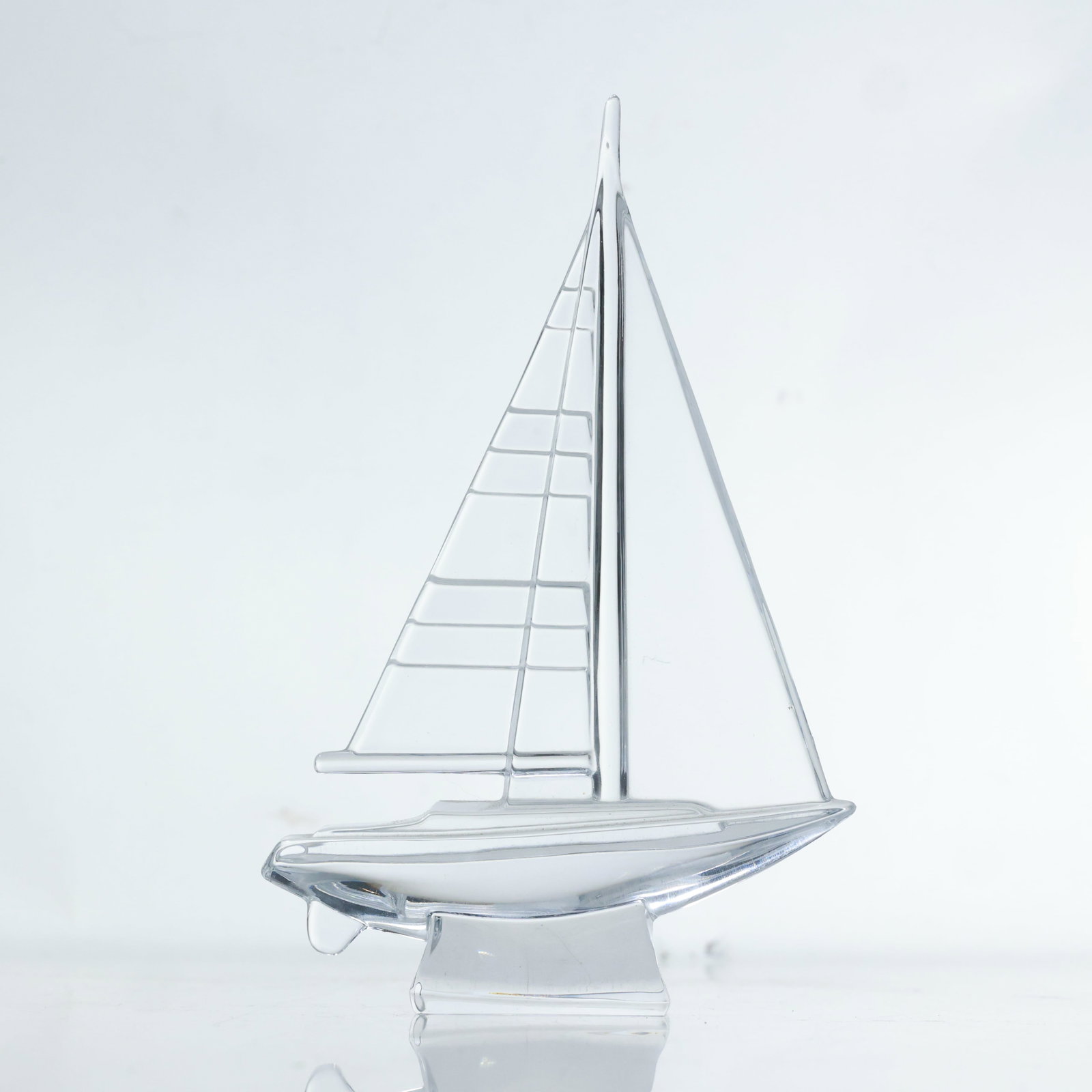 Signed JG Durand Nautical Modern Glass Sailboat Sculpture 8.25 in. height x 5.5 in. wide: This glass sailboat sculpture, signed by JG Durand, features a sleek and modern design. The sculpture is clear and captures the form of a sailboat with minimalist lines. The hull is smooth and streaml