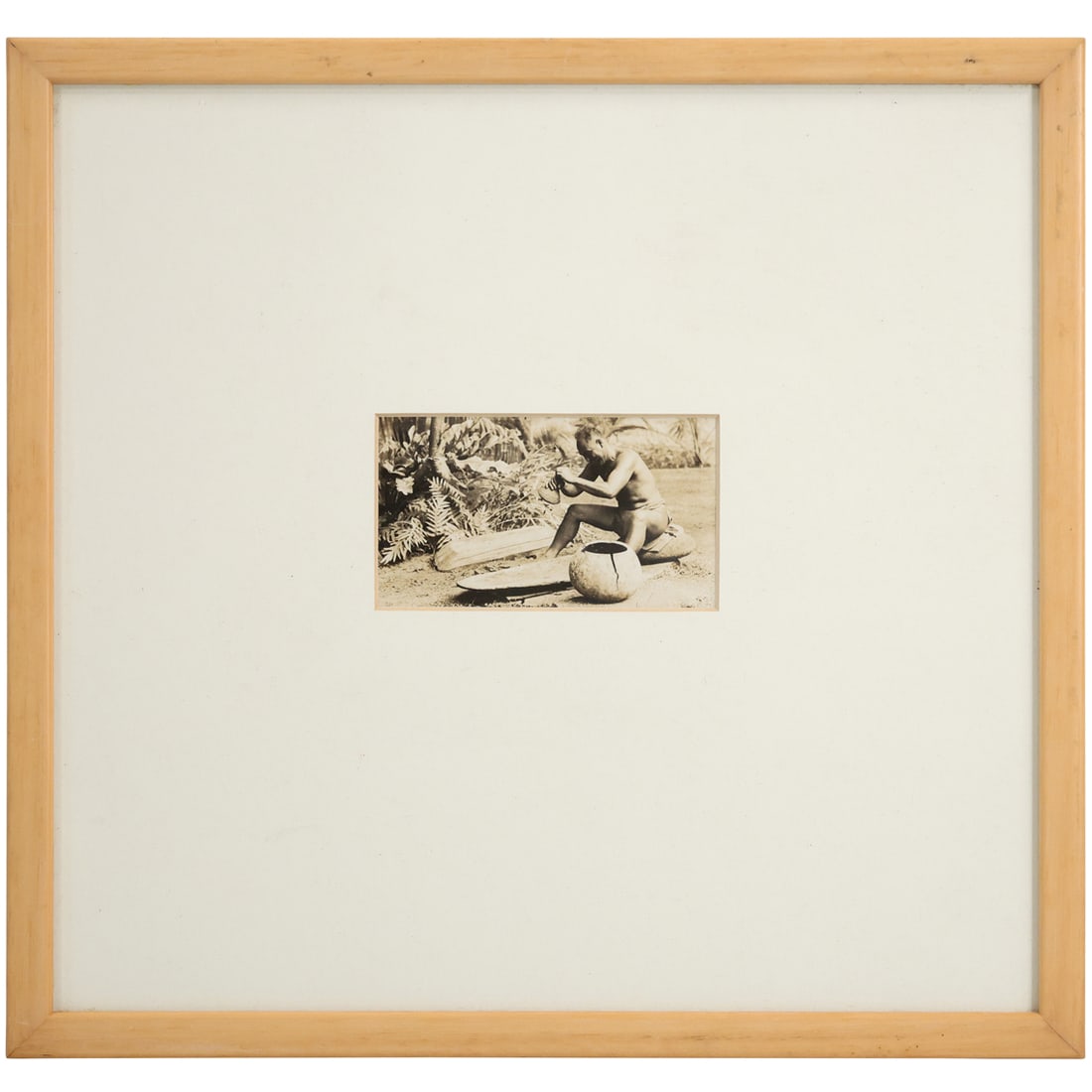 Photograph. A Hawaiian man wearing a traditional malo sits on a stone while he grind food (1 of 9)