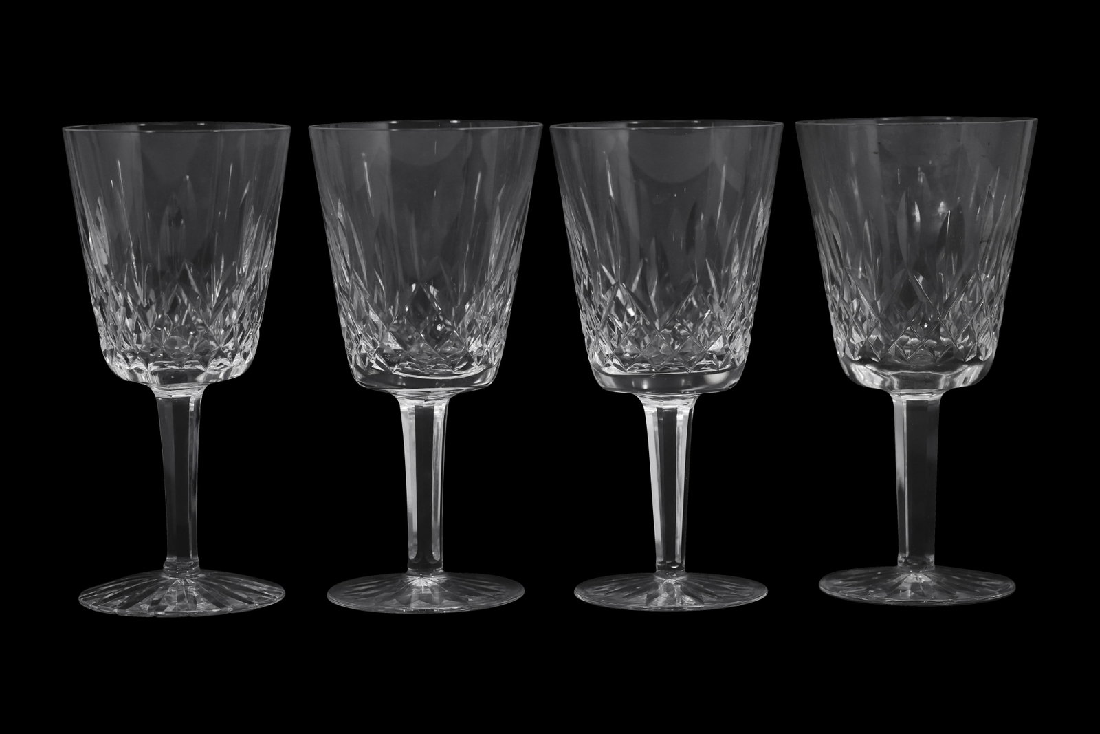 Set of Four Waterford Crystal Wine Glasses: Set of four marked Waterford crystal wine glasses featuring a faceted cut design with vertical panels transitioning into cross-cut diamond motifs. Each glass is crafted from fine lead crystal, exhibit