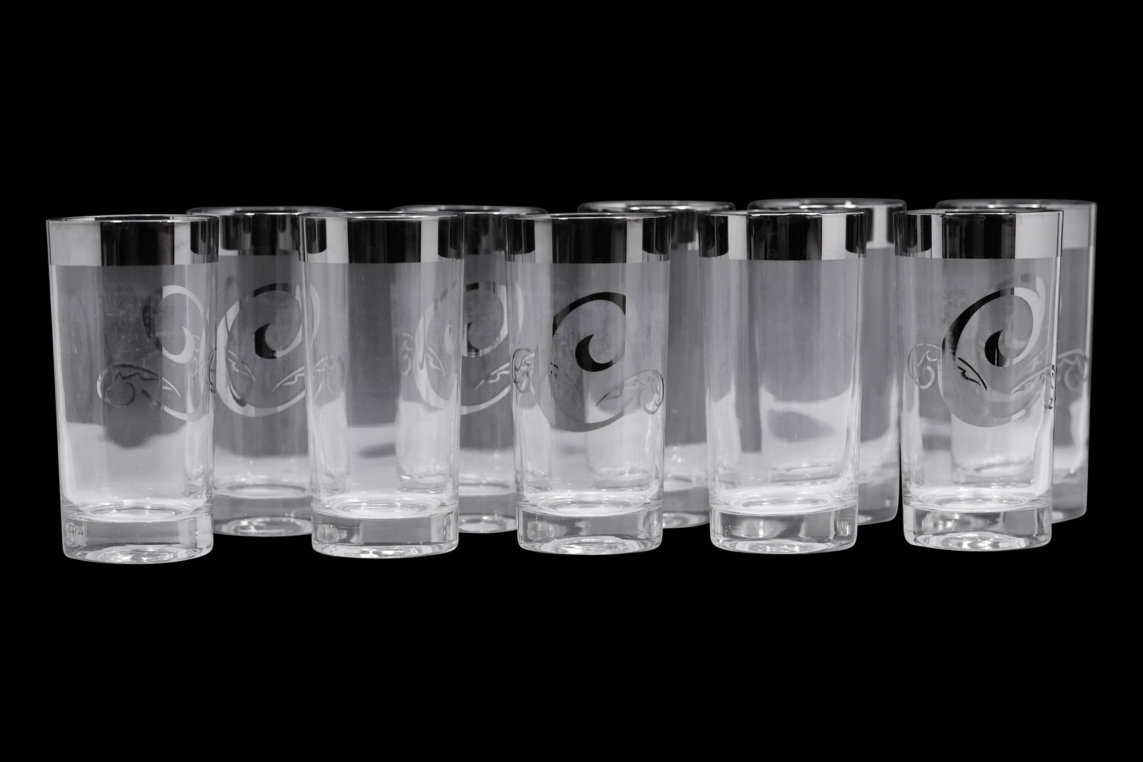Set of 8 Silver Rim Monogram C Highball Glasses, in the Style of Dorothy Thorpe: Set of eight clear glass highball tumblers featuring a polished silver rim and etched scroll monogram C motif. Each glass exhibits a cylindrical form with thick base and reflective upper band. The mon