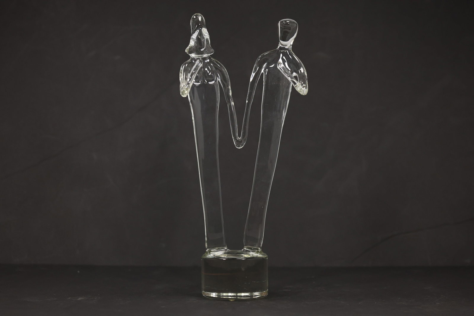 Artist Signed Clear Art Glass Sculpture Couple Holding Hands: Clear art glass sculpture featuring an embracing couple on a base size: 13h 6w S:C** Important Auction information:**** All lot descriptions in this auction were generated using artificial intelligenc