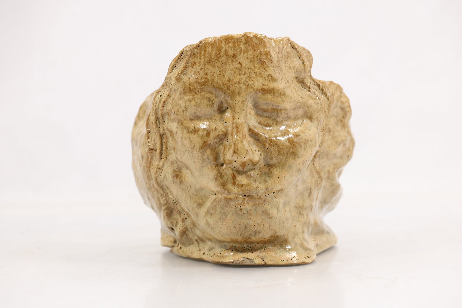 Artist Signed Ceramic Figural Head Sculpture: Hand formed ceramic sculpture depicting a stylized human face with closed eyes and softly modeled features. The piece is finished in a light cream glaze with visible texture and sculptural tool marks 
