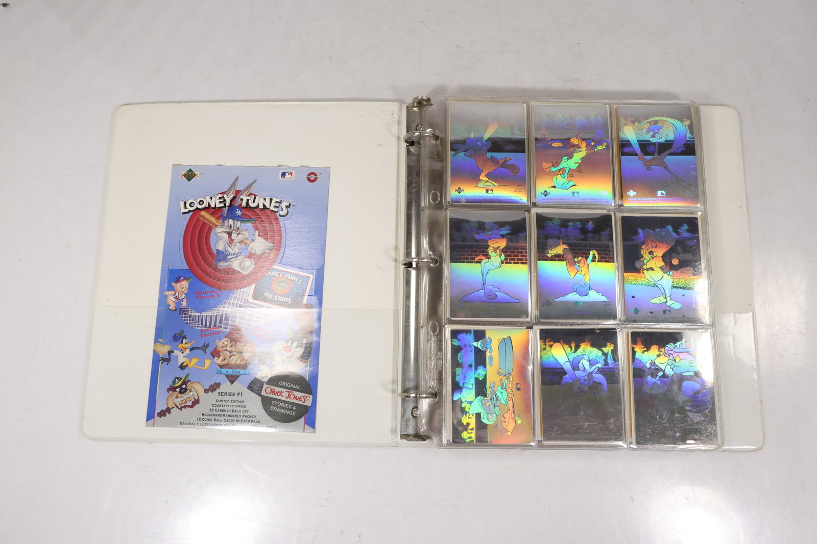 Looney Tunes Trading Card Collection in Binder Including Holographic Cards: Collection of Looney Tunes trading cards housed in a three-ring binder with plastic card sleeves. The assortment includes numerous character cards featuring Bugs Bunny, Daffy Duck, Sylvester, Tweety, 