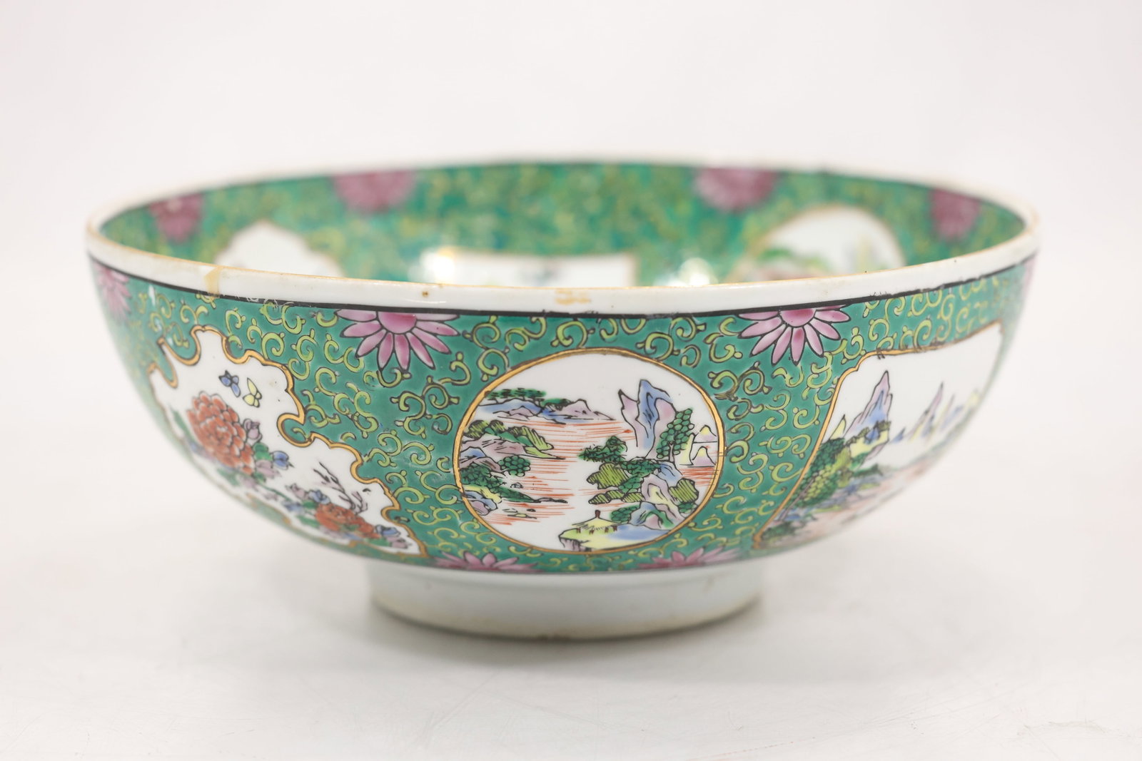 Japanese Kutani Style Porcelain Bowl with Landscape and Floral Panels: Porcelain bowl decorated with a turquoise green ground featuring gilt scrolling ornament and alternating cartouche panels. The exterior displays landscape scenes with mountains rivers and trees alongs