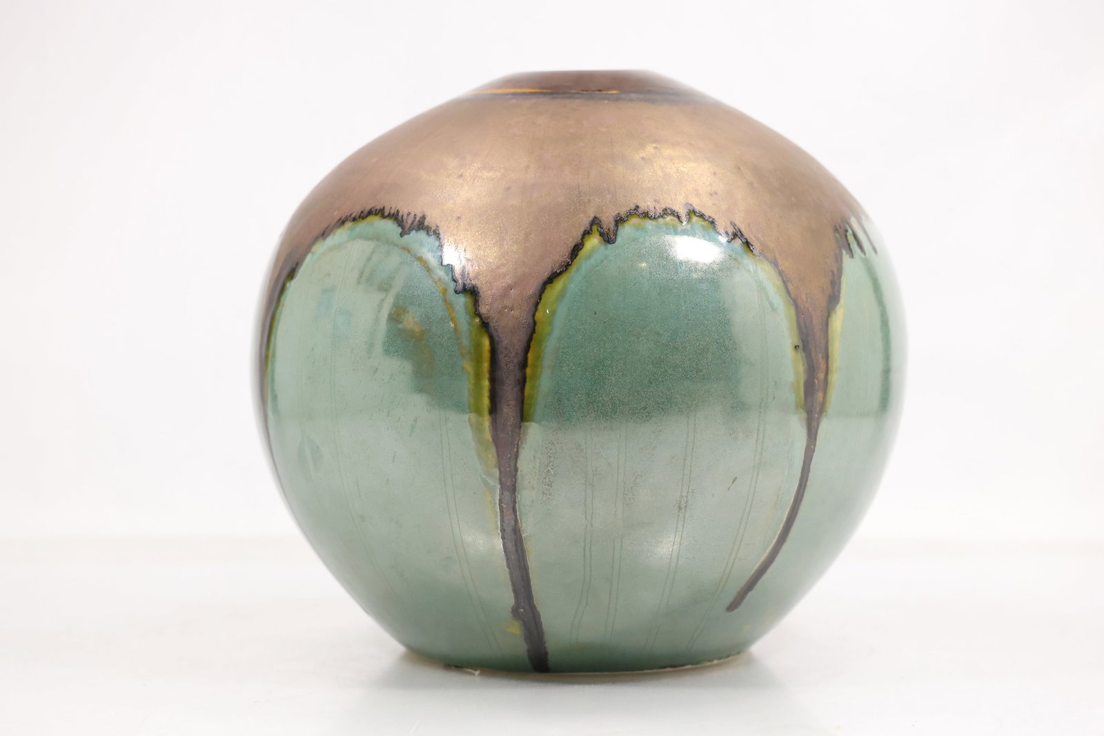 Large Spherical Studio Pottery Vase with Bronze and Sea Green Glaze: Large spherical ceramic vase with a small circular mouth. The lower body has a sea green glaze while the upper section has a metallic bronze brown glaze that descends in irregular drips. The base is