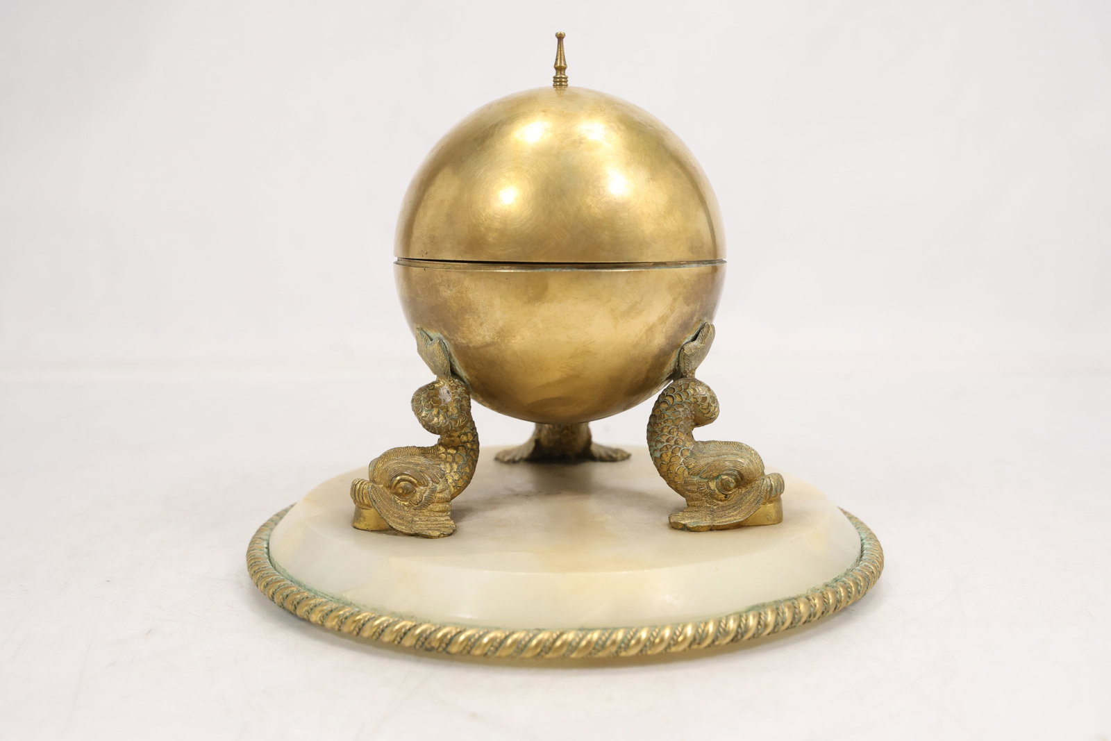 Gilt Metal and Alabaster Figural Dolphin Inkwell on Alabaster Base: Decorative desk inkwell featuring a hinged gilt metal spherical cover supported by three dolphin-form feet atop a circular alabaster base. The interior retains a circular mount designed to hold a remo