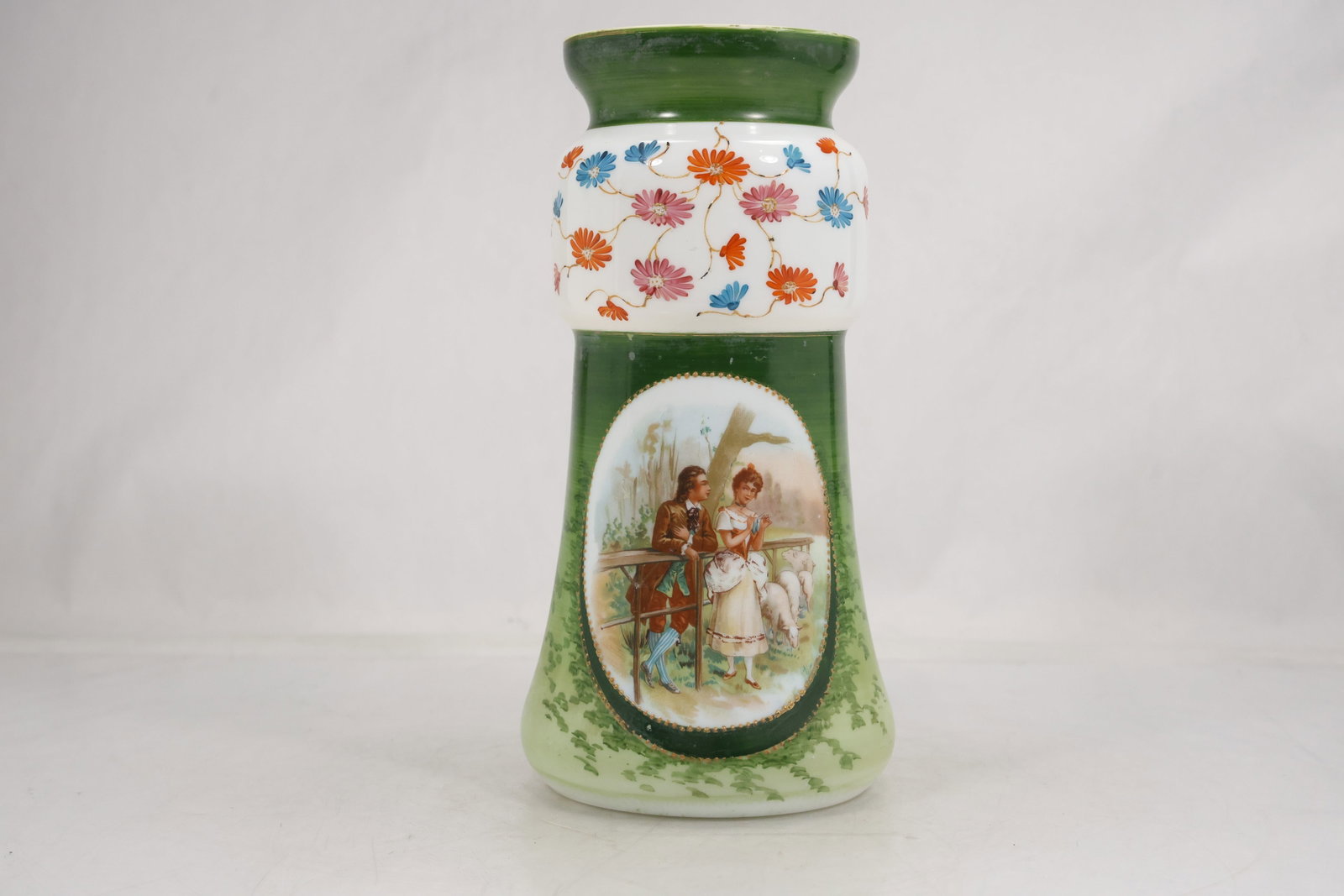 Green Portrait and Floral Decorated Ceramic Vase: Tall ceramic vase with a green ground flared rim hand painted floral decoration and an oval female portrait reserve. White and multicolor bands frame the upper body while the lower section shifts thro