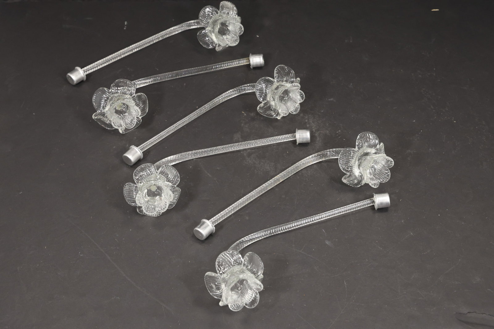 Set of Six Clear Murano Glass Flower Chandelier Stems: Set of six vintage mid century Murano glass clear flower chandelier stems from confirmed importer stock. Each curved clear support ends in a layered transparent blossom with scalloped petals and a rai