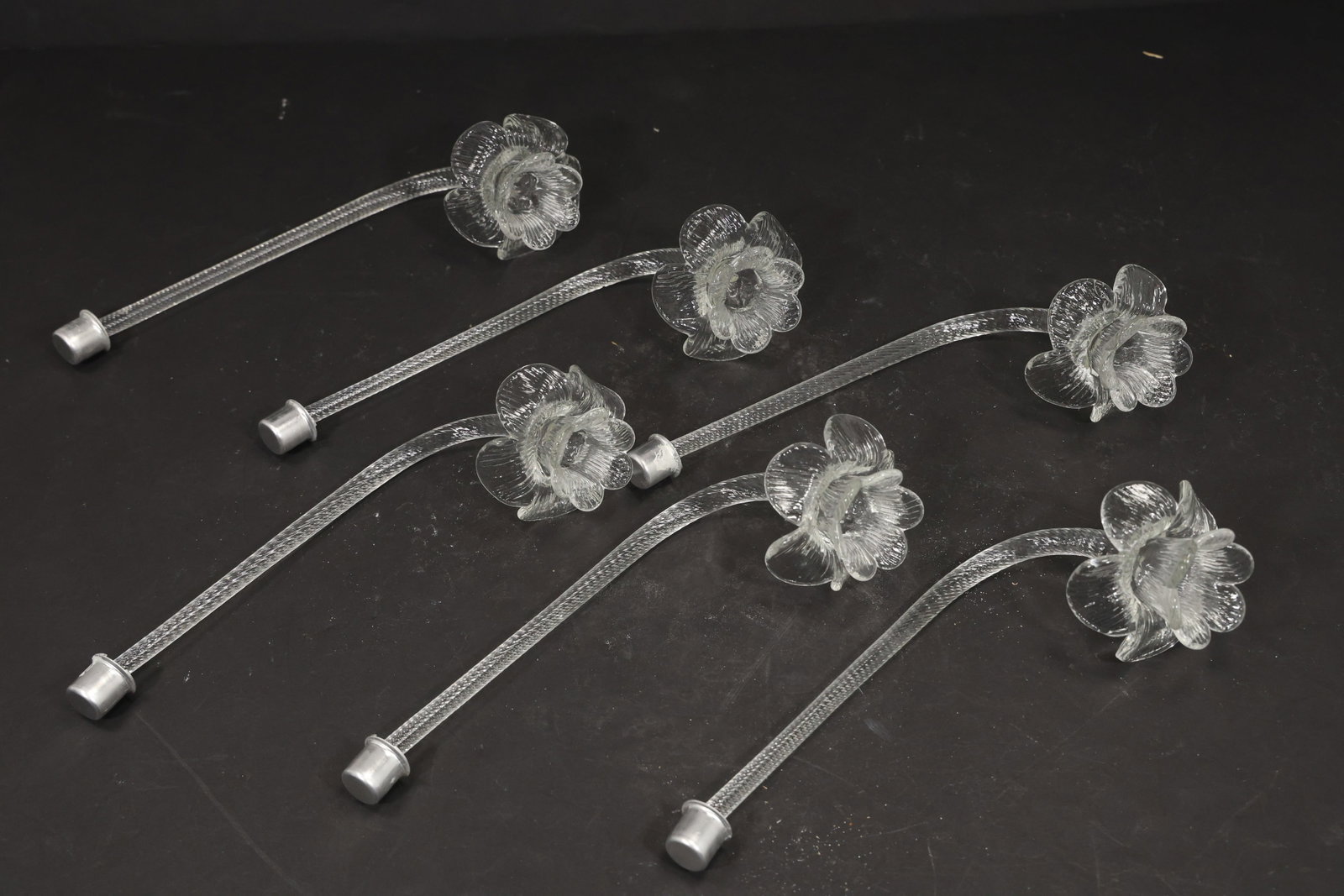 Set of Six Clear Murano Glass Flower Chandelier Stems: Set of six vintage mid century Murano glass clear flower chandelier stems from confirmed importer stock. Each curved transparent support terminates in a layered blossom with textured petals and a rais