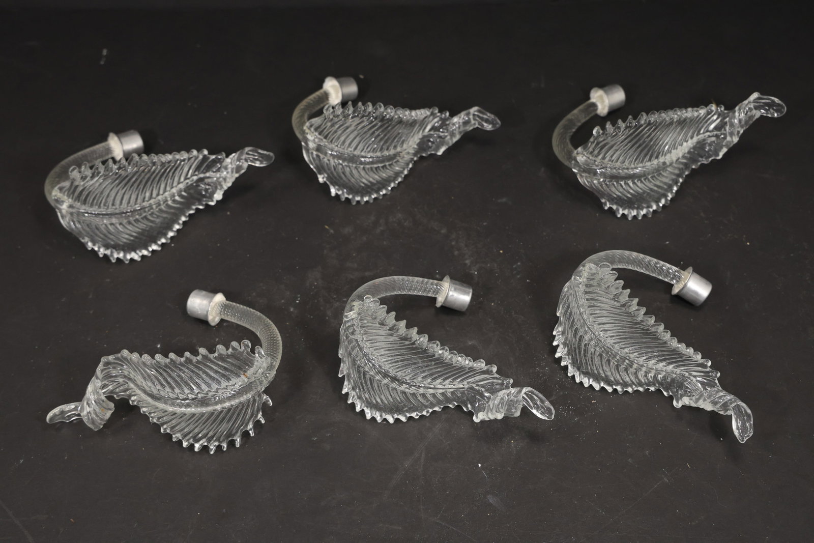 Set of Six Clear Murano Glass Curled Leaf Chandelier Parts: Set of six vintage mid century Murano glass clear curled foliage chandelier replacement parts from confirmed importer stock. Each compact element has a curved stem ribbed leaf body serrated edge and t