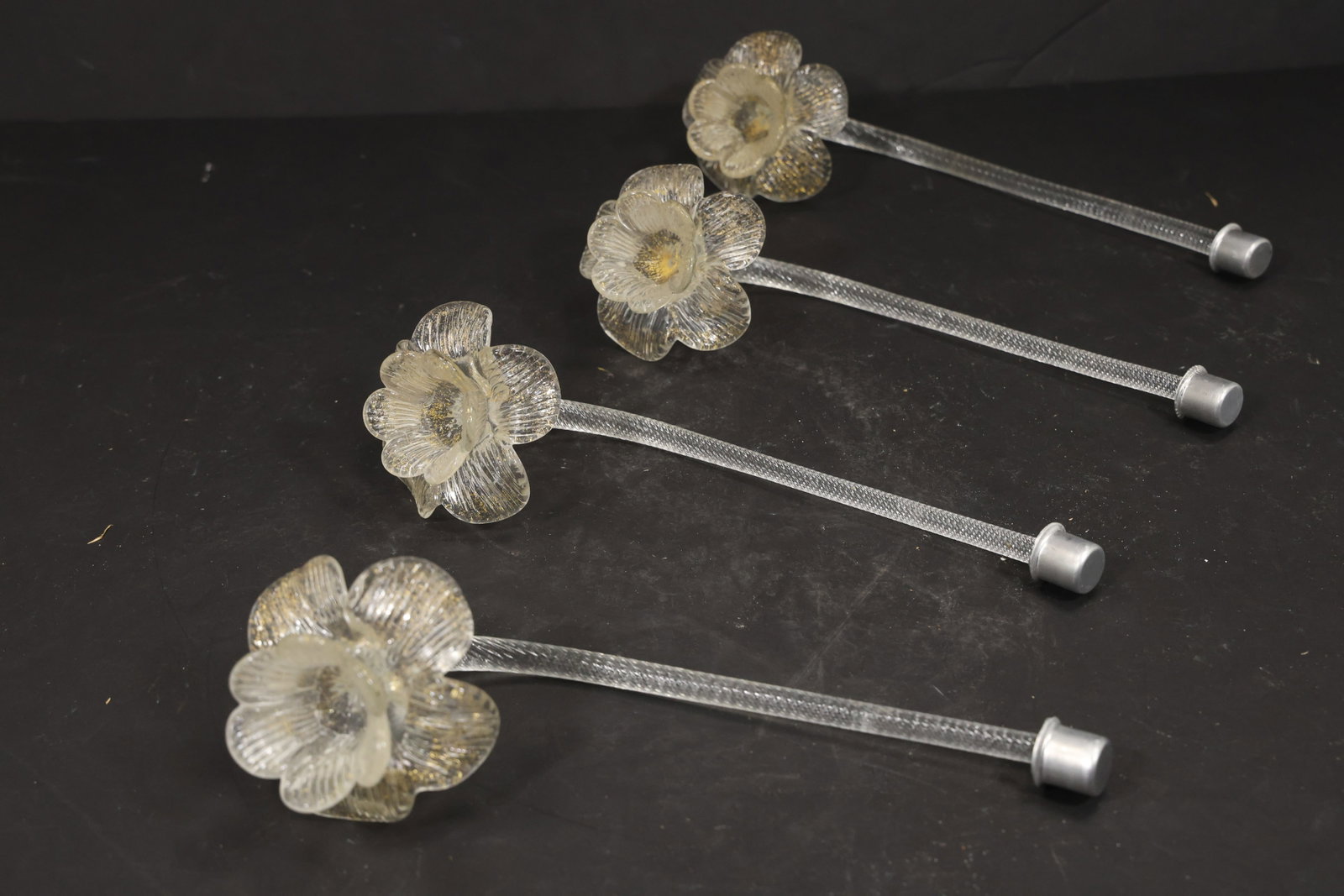Set of Four Clear Gold Fleck Murano Glass Flower Chandelier Stems: Set of Four vintage mid century Murano glass flower chandelier stems from confirmed importer stock. Photographs show curved or straight supports ending in layered blossoms with modeled petals in clear