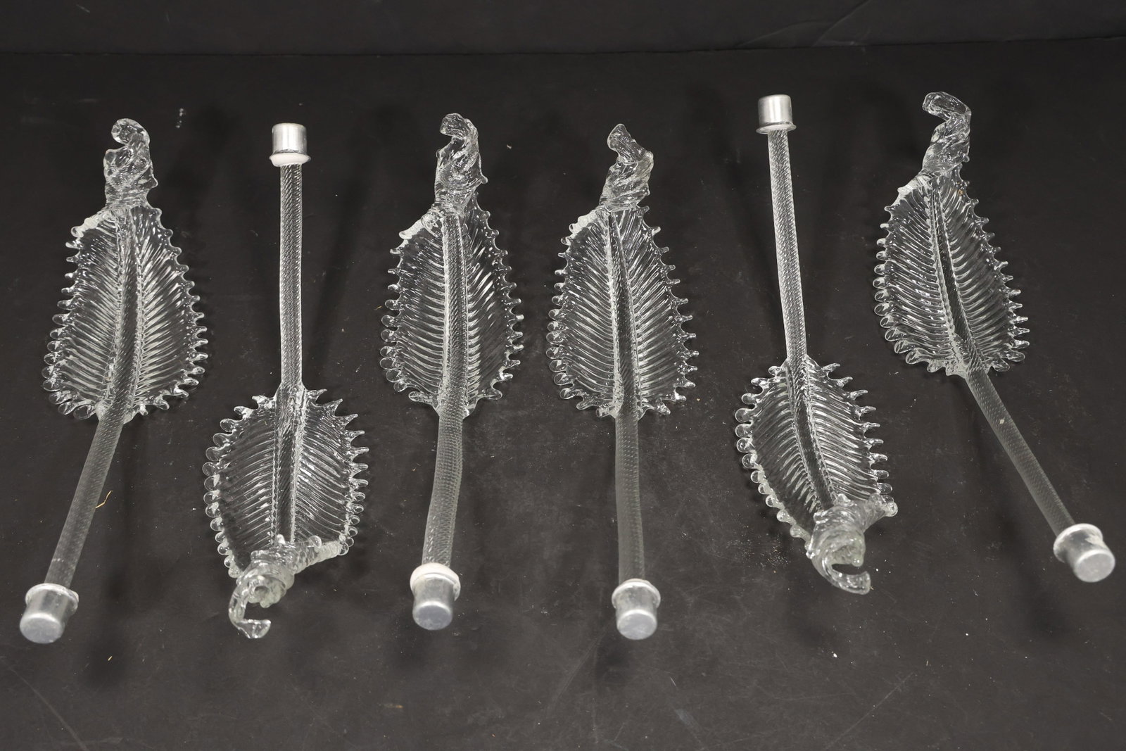 Set of Six Clear Murano Glass Leaf Chandelier Stems: Set of Six vintage mid century Murano glass foliage chandelier stems from confirmed importer stock. Photographs show ribbed leaf bodies with serrated edges and mounting ends in clear tones. Suitable a