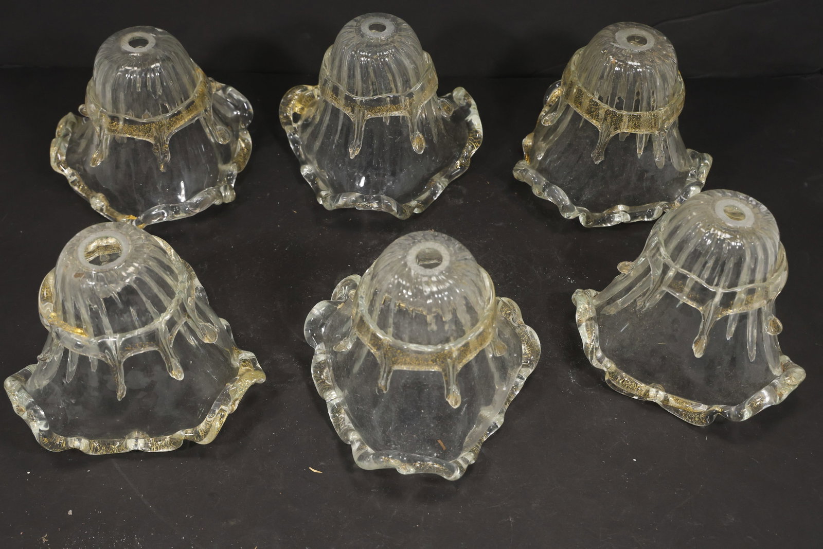 Set of Six Clear Gold Fleck Murano Glass Chandelier Shades: Set of Six vintage mid century Murano glass chandelier shades from confirmed importer stock. Photographs show flared or domed bodies with central apertures and decorative rims in clear gold fleck tone