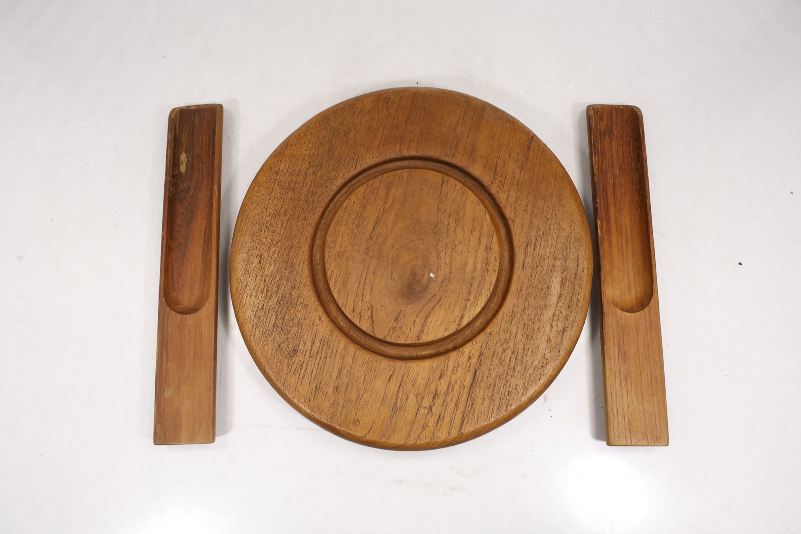 Mid-Century Danish Modern Teak Wood Serving Set, 3 Pieces: Three-piece mid-century modern teak wood serving set comprising a circular serving trivet or plate and two matching shaped teak accessories. Crafted from solid teak with a warm natural grain and minim