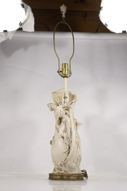 Porcelain Lady Figural Lamp: Tall porcelain figural lamp modeled as a standing woman in flowing dress with decorative applied details and metal lighting hardware. The pale glazed figure rises from an integral base and is presente