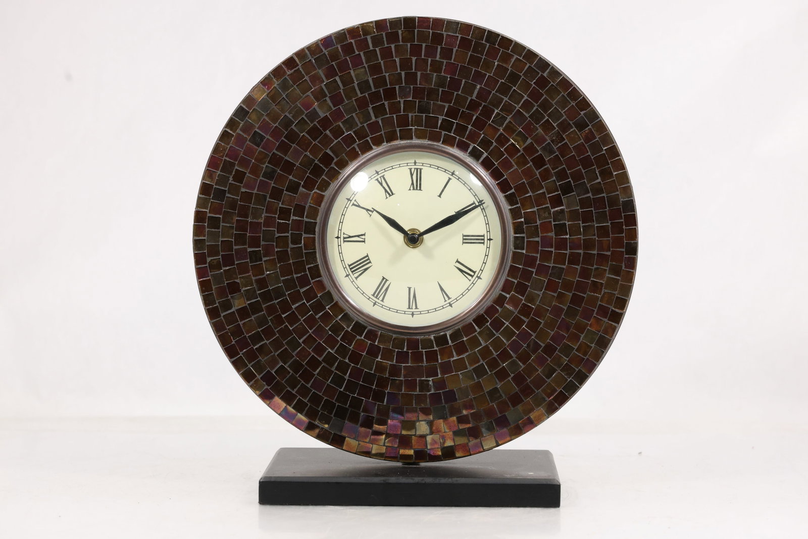 Baltic Amber Mosaic Tiled Clock with Base: Decorative desk clock featuring a circular face surrounded by a mosaic of small amber-toned tiles, creating a rich, textured surface with warm brown, honey, and cognac hues. The design gives a subtle 