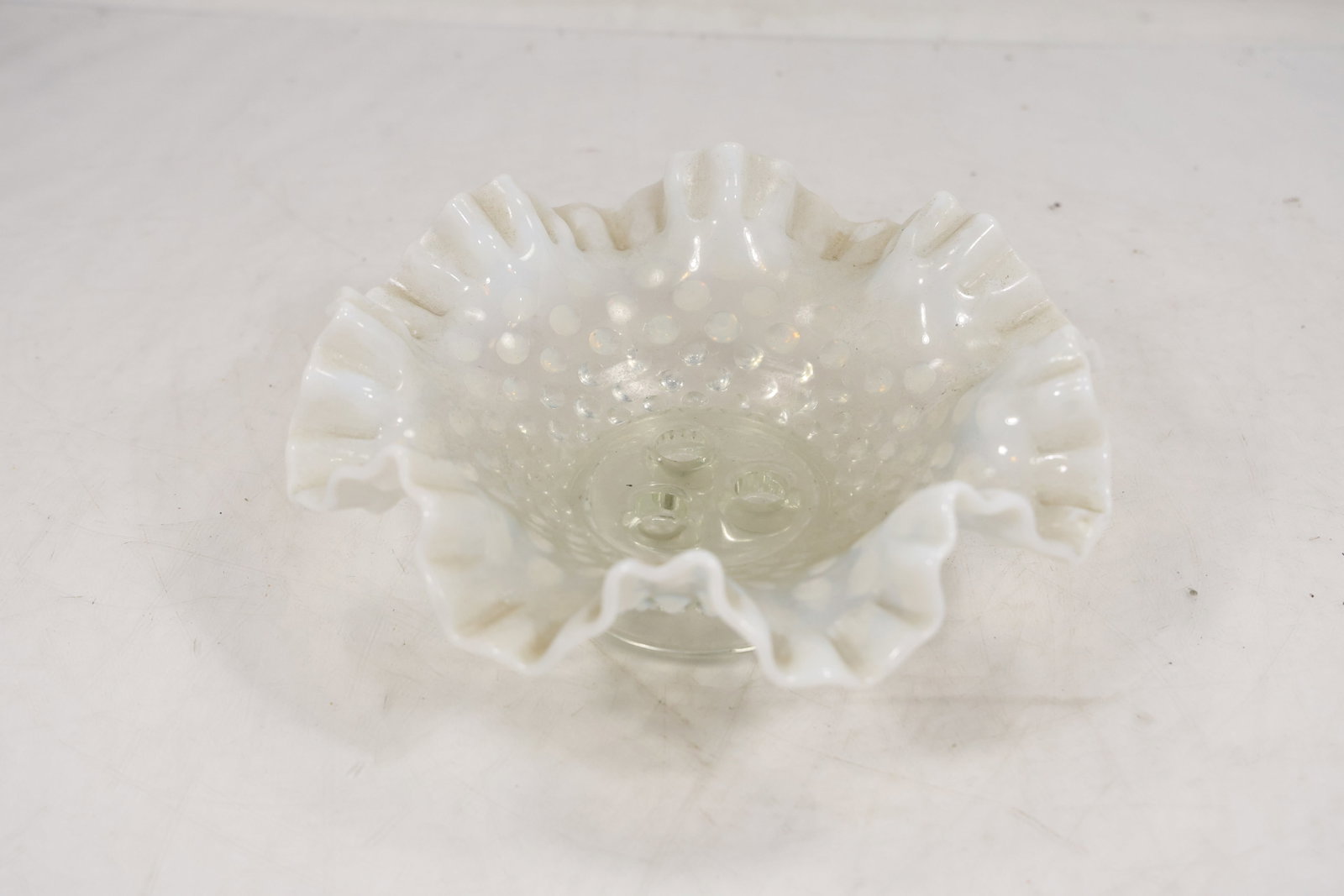 Fenton Hobnail Milk Glass Ruffled Compote Bowl: Decorative milk glass bowl featuring the classic hobnail pattern with a deeply ruffled and crimped rim. The bowl is raised on a short pedestal foot and displays the distinctive opaque white coloration