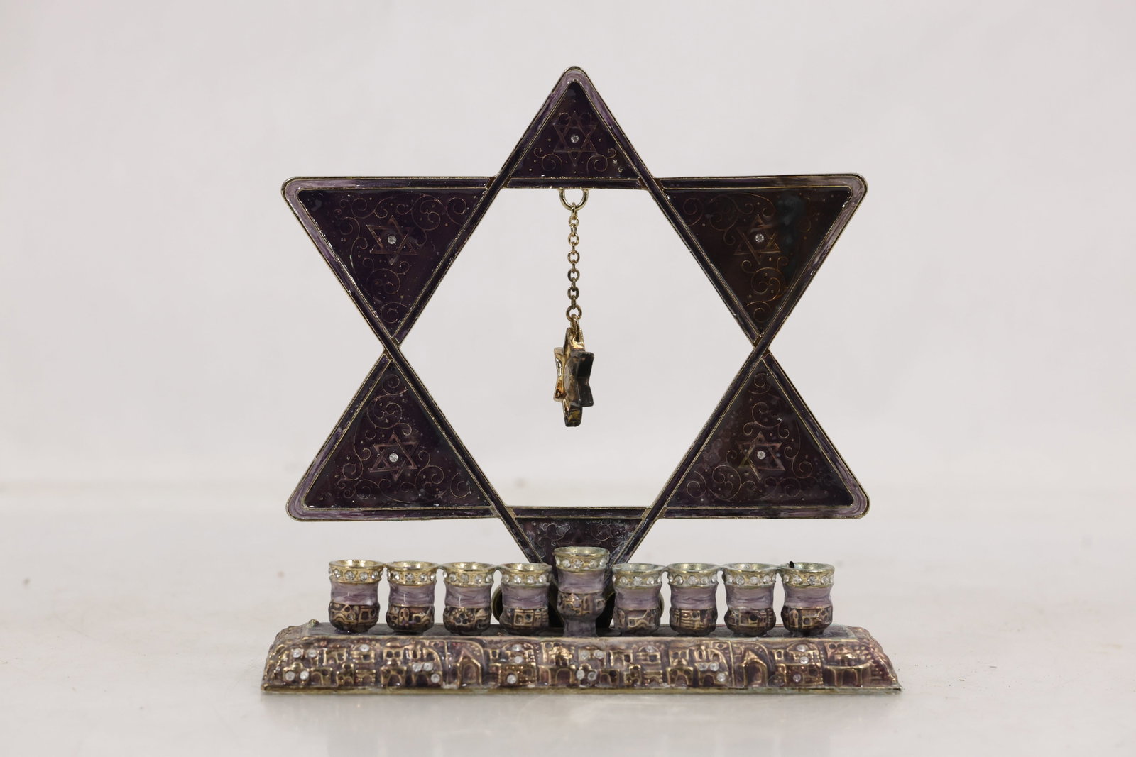 Judaica Style Star of David Menorah with Enamel Panels and Oil Cup Holders DV Amy Mark: Decorative menorah featuring a six point Star of David form constructed with triangular panels filled in deep purple enamel and scrolling motifs. The structure is mounted on a cast metal base with rel
