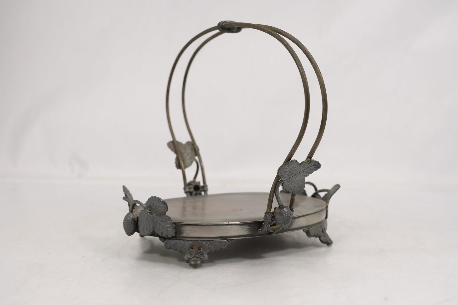 Meriden Britannia Company Silver Plate Basket Form Stand with Figural Strawberry Motif: Silver plate stand or basket form piece with circular tray base and arched handle supports. The rim and supports are decorated with cast strawberry fruit and leaf motifs, with additional scrollwork de