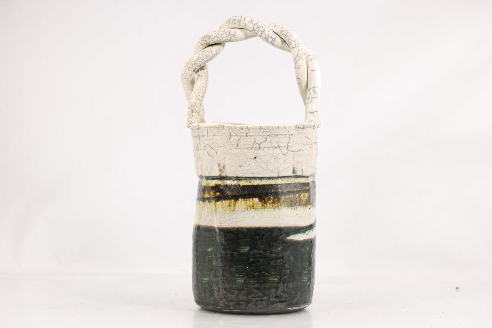 Ken Willingham Signed Studio Pottery Basket Vase with Twisted Handle: Hand built studio pottery basket form vase with a tall cylindrical body and twisted overhead handle. The vessel has a dark textured lower section with green and turquoise glaze accents separated by cr