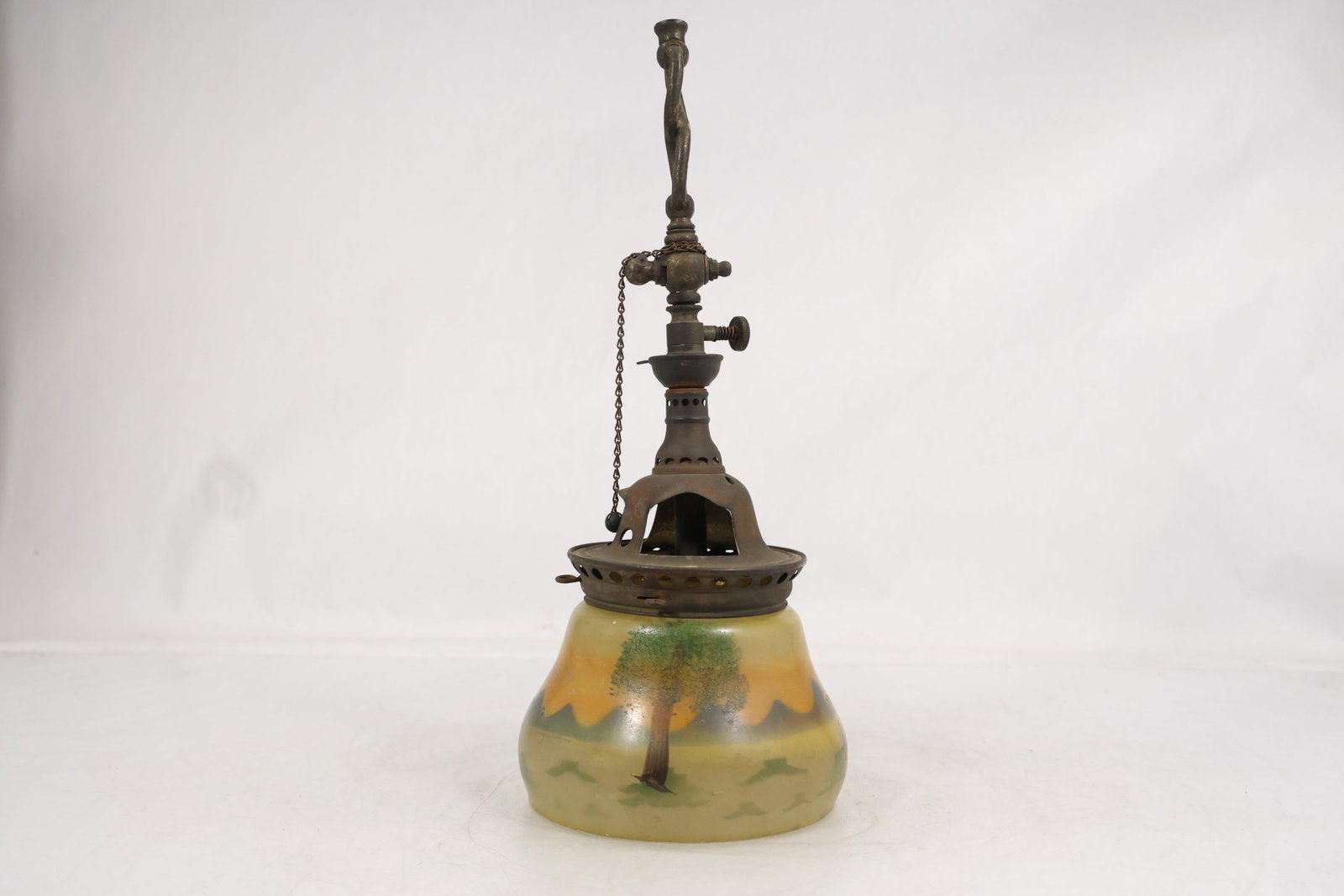 Antique Welsbach Reflex Inverted Gas Lamp with Painted Landscape Glass Shade: Antique Welsbach inverted gas lamp fitted with a bell form glass shade decorated with a painted landscape of trees distant mountains fence and warm yellow sky. The metal burner assembly features a pie
