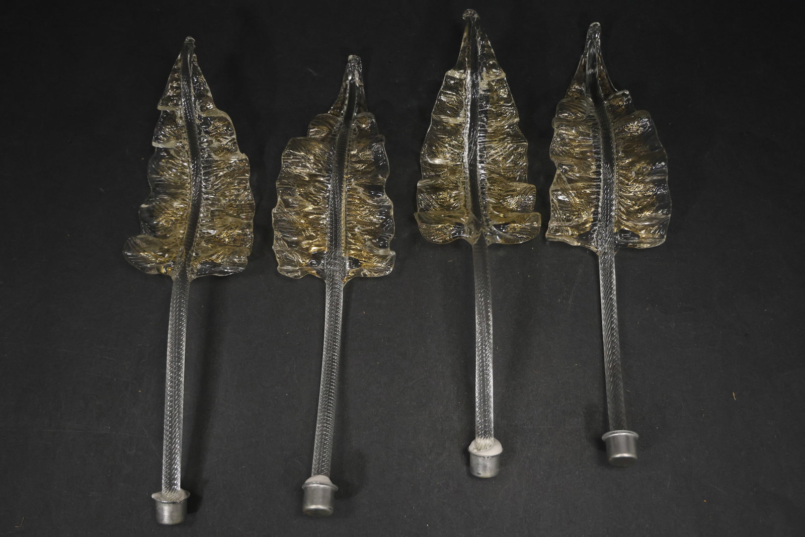 Set of Four Clear Gold Fleck Murano Glass Leaf Chandelier Stems: Set of Four vintage mid century Murano glass foliage chandelier stems from confirmed importer stock. Photographs show ribbed leaf bodies with serrated edges and mounting ends in clear gold fleck tones