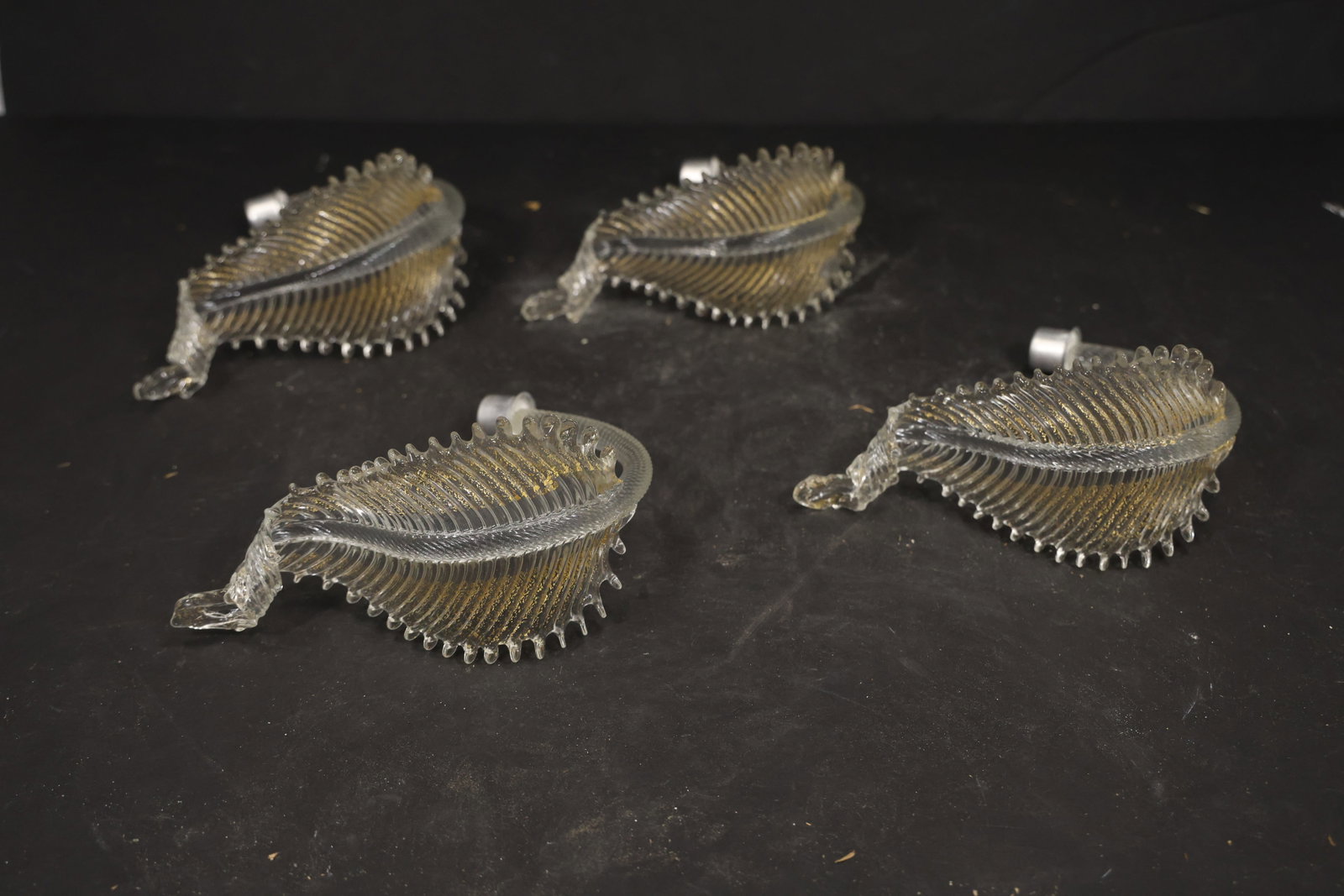Set of Four Clear Gold Fleck Murano Glass Leaf Chandelier Stems: Set of Four vintage mid century Murano glass foliage chandelier stems from confirmed importer stock. Photographs show ribbed leaf bodies with serrated edges and mounting ends in clear gold fleck tones