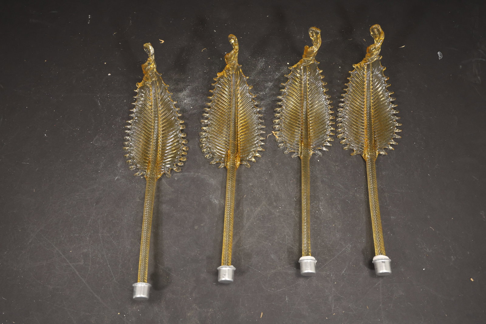 Set of Four Amber Yellow Murano Glass Leaf Chandelier Stems: Set of Four vintage mid century Murano glass foliage chandelier stems from confirmed importer stock. Photographs show ribbed leaf bodies with serrated edges and mounting ends in amber yellow tones. Su