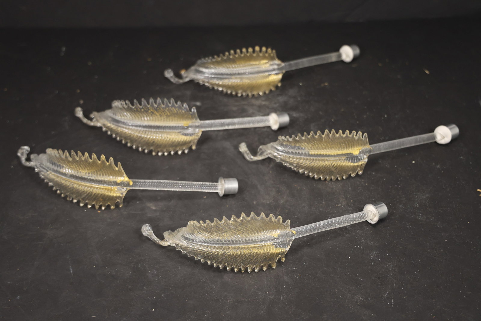Set of Five Clear Gold Fleck Murano Glass Leaf Chandelier Stems: Set of Five vintage mid century Murano glass foliage chandelier stems from confirmed importer stock. Photographs show ribbed leaf bodies with serrated edges and mounting ends in clear gold fleck tones