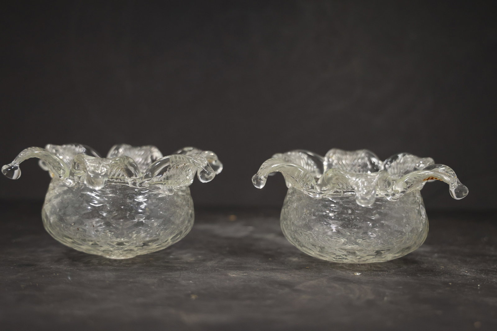 Pair Clear Murano Glass Lobed Chandelier Shades: Pair of vintage mid century Murano glass lobed flower form chandelier shades from confirmed importer stock. Photographs show wide sculptural bowls with curling petal edges and central apertures in cle
