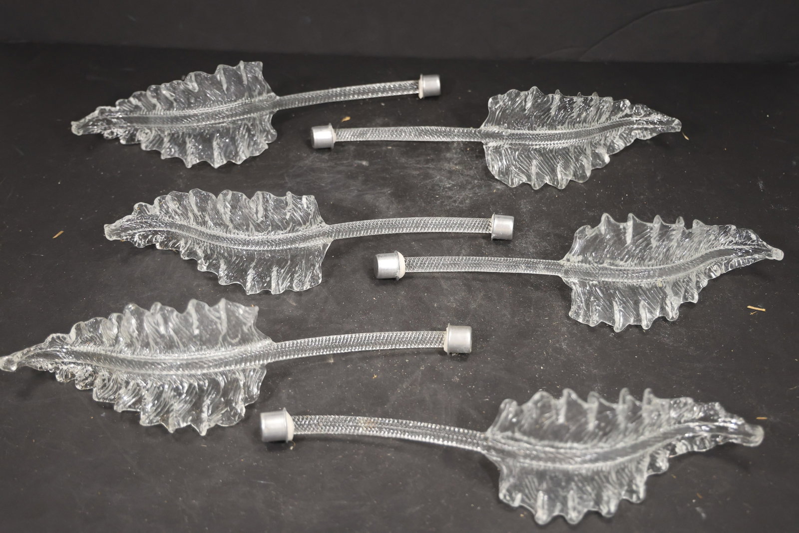 Set of Six Clear Murano Glass Leaf Chandelier Stems: Set of Six vintage mid century Murano glass foliage chandelier stems from confirmed importer stock. Photographs show ribbed leaf bodies with serrated edges and mounting ends in clear tones. Suitable a