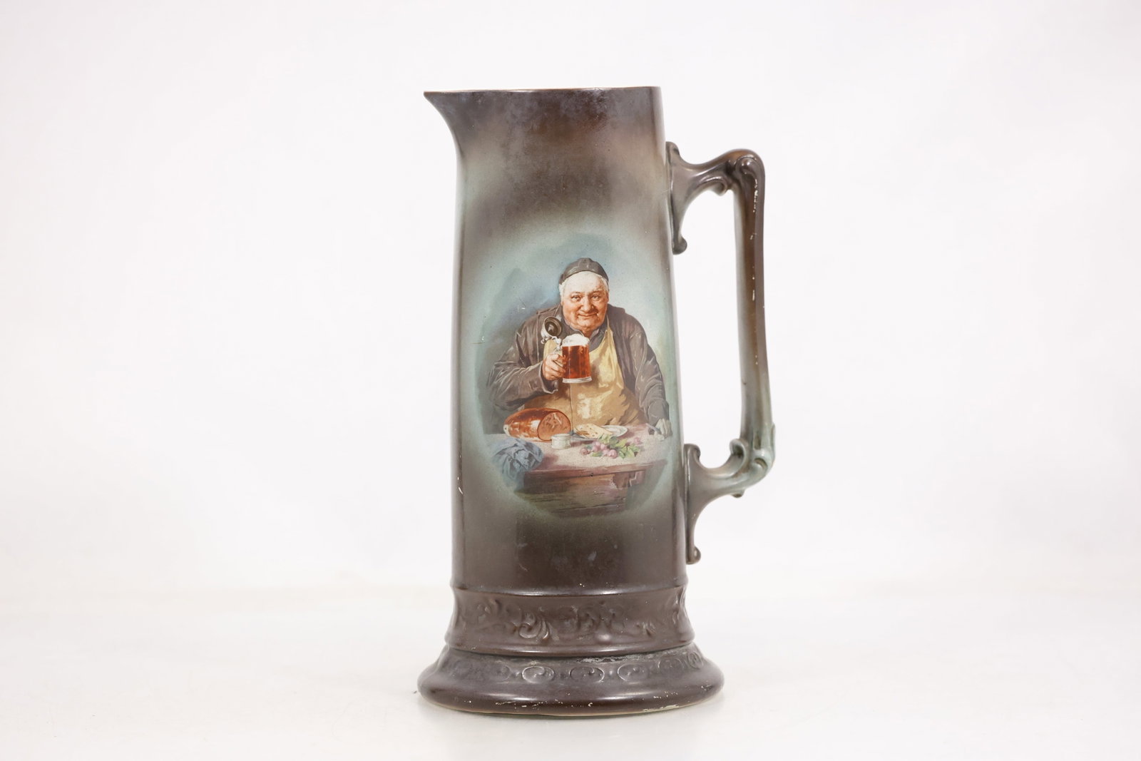 Decorative Ceramic Tankard Pitcher with Figural Scene: Photographs show decorative ceramic tankard pitcher with figural scene in glazed ceramic or pottery with the visible form color and decorative motifs described directly from the images. No unverified 