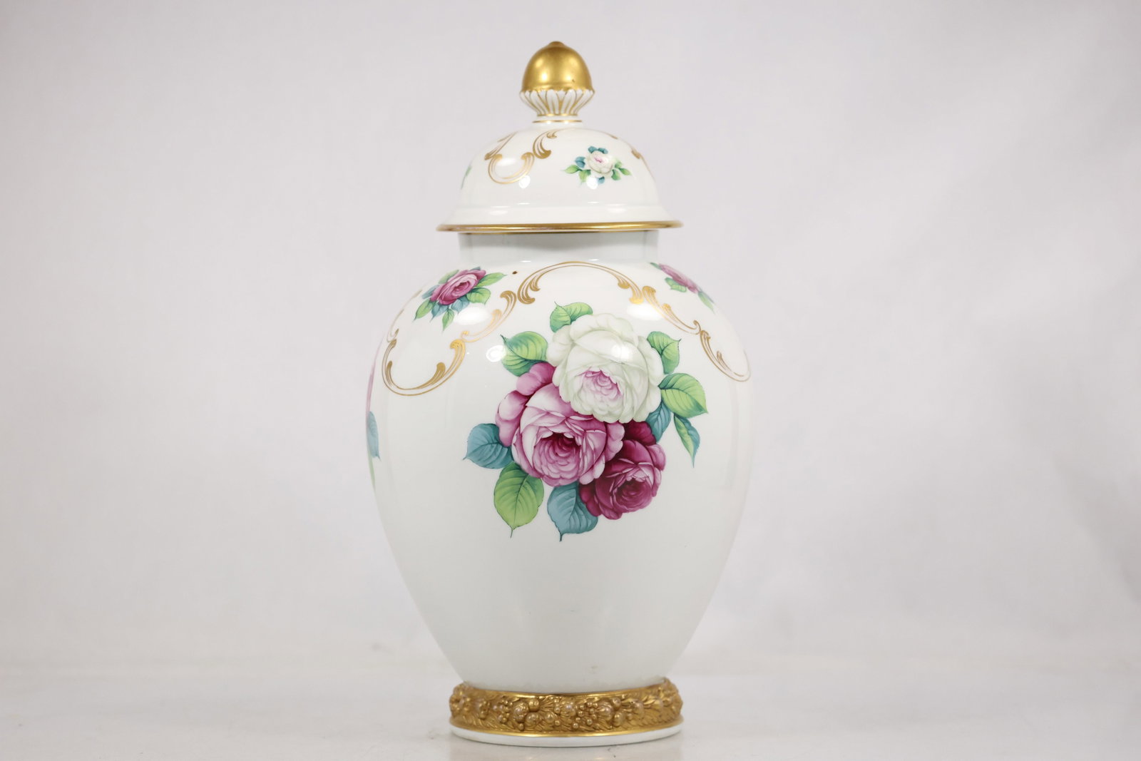 Rosenthal Floral Porcelain Covered Urn: Rosenthal glazed porcelain covered urn with a cream white ground hand painted floral decoration gilt accents and a fitted domed lid with finial. The photographed Rosenthal identification supports the 