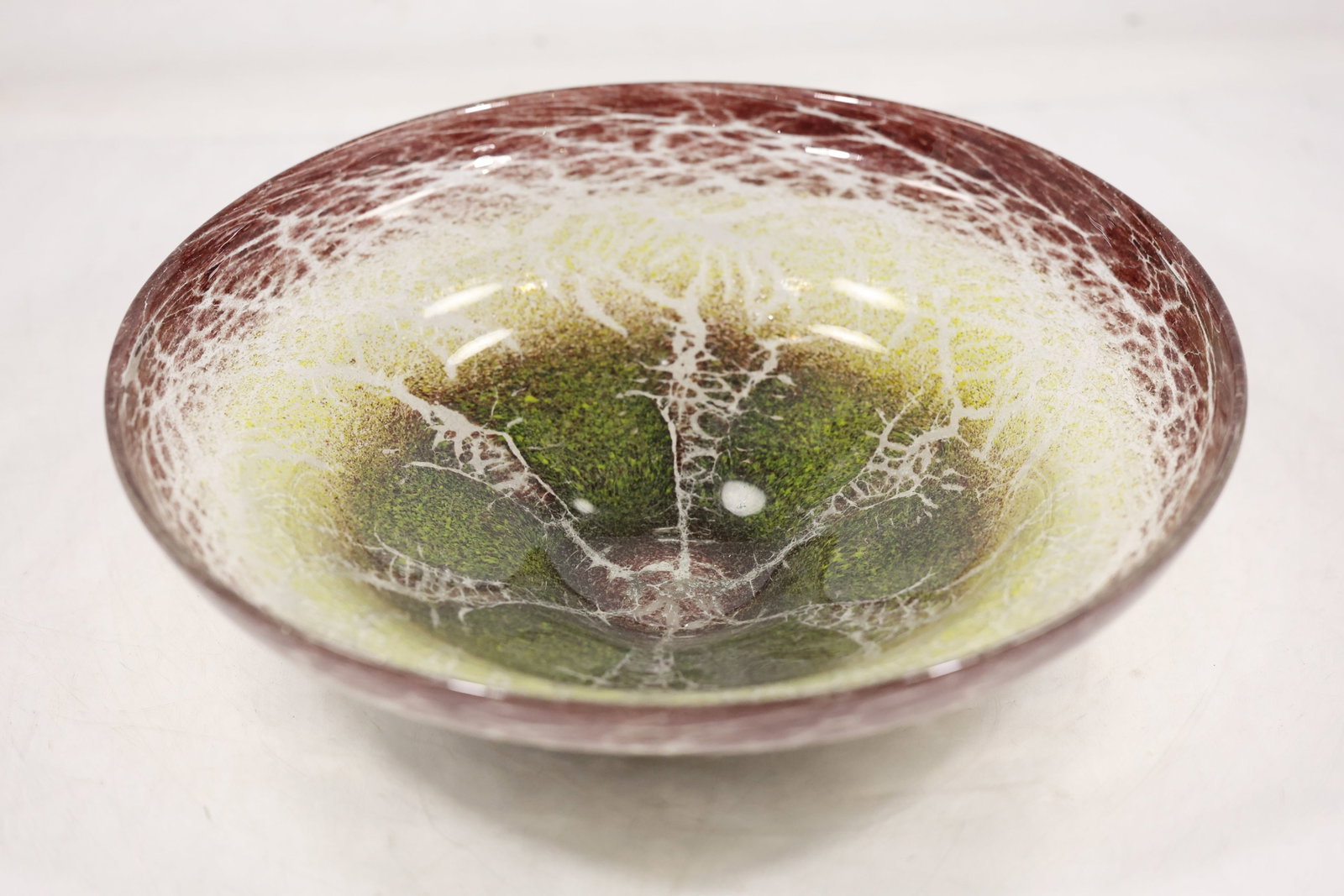 Crackle Glass Bowl with Green Center: A shallow clear crackle glass bowl has an irregular rounded form and concentrated green color at the center. The controlled crackle surface and color transition are visible in the photographs and no m