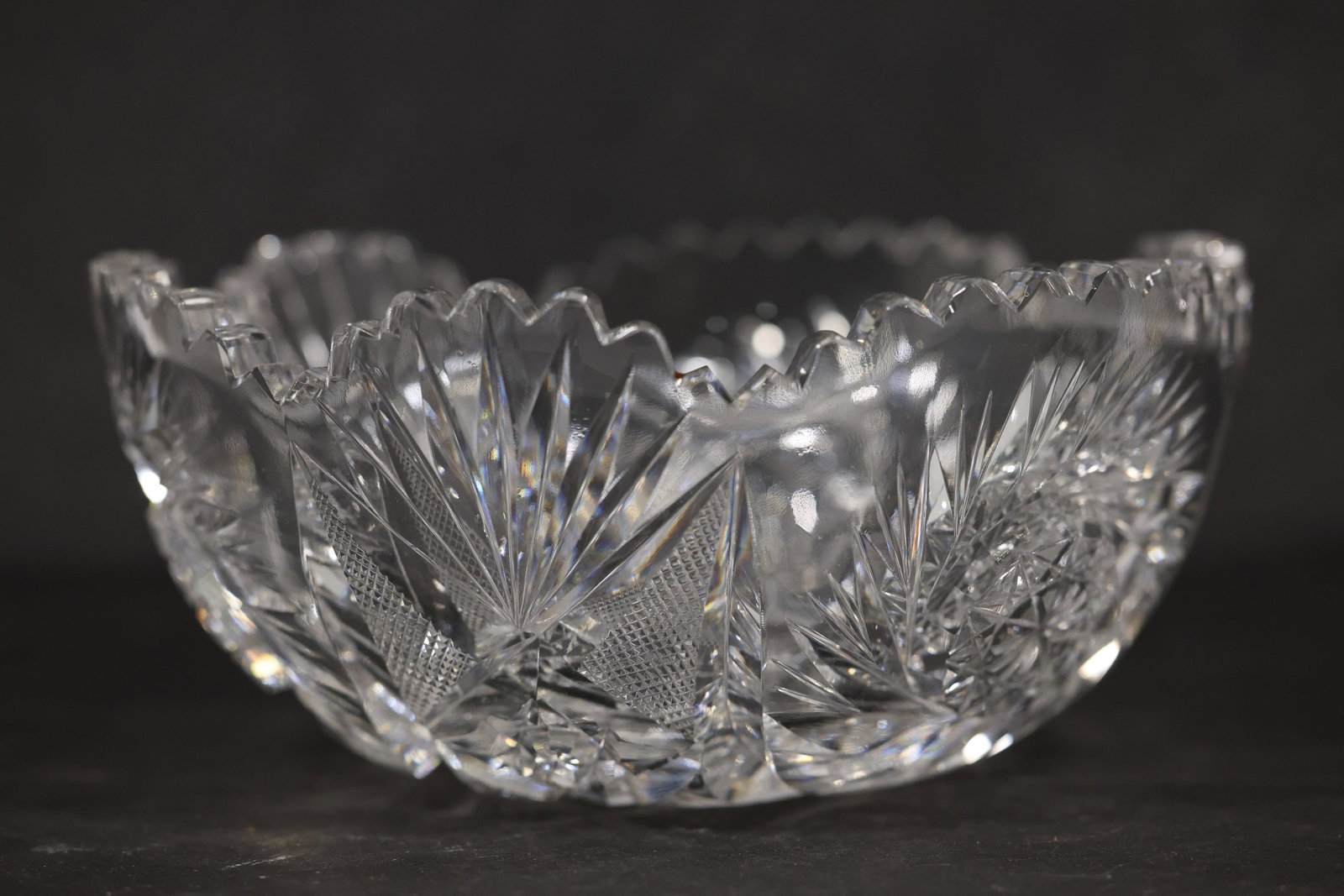 Cut Crystal Bowl with Floral Motif: A clear crystal bowl has a flared circular form with faceted cutting and floral inspired decoration. The repeated cut pattern and heavy transparent body identify it as decorative crystal tableware and