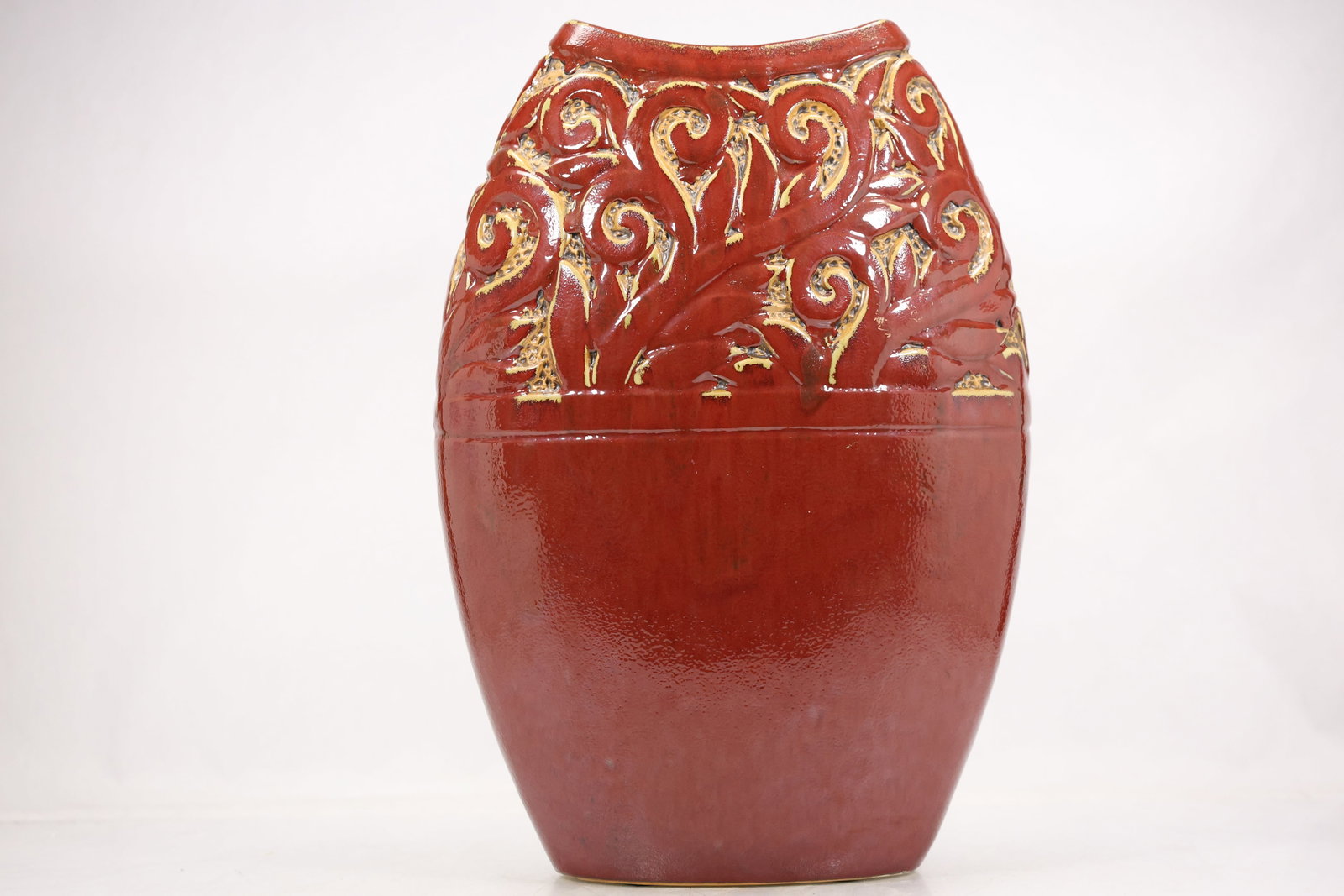 Large Red Pottery Vase with White Sgraffito Motifs: A large red glazed pottery vase has a broad rounded body narrow mouth and white incised sgraffito style motifs. The contrasting linear decoration and substantial vessel form are visible in the photogr