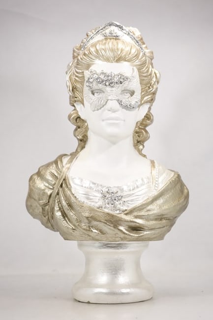 White and Gold Masked Female Bust Sculpture: A decorative bust depicts a masked woman with a white surface and gold tone accents. The theatrical mask stylized face and shoulder length sculptural format support a Venetian carnival style