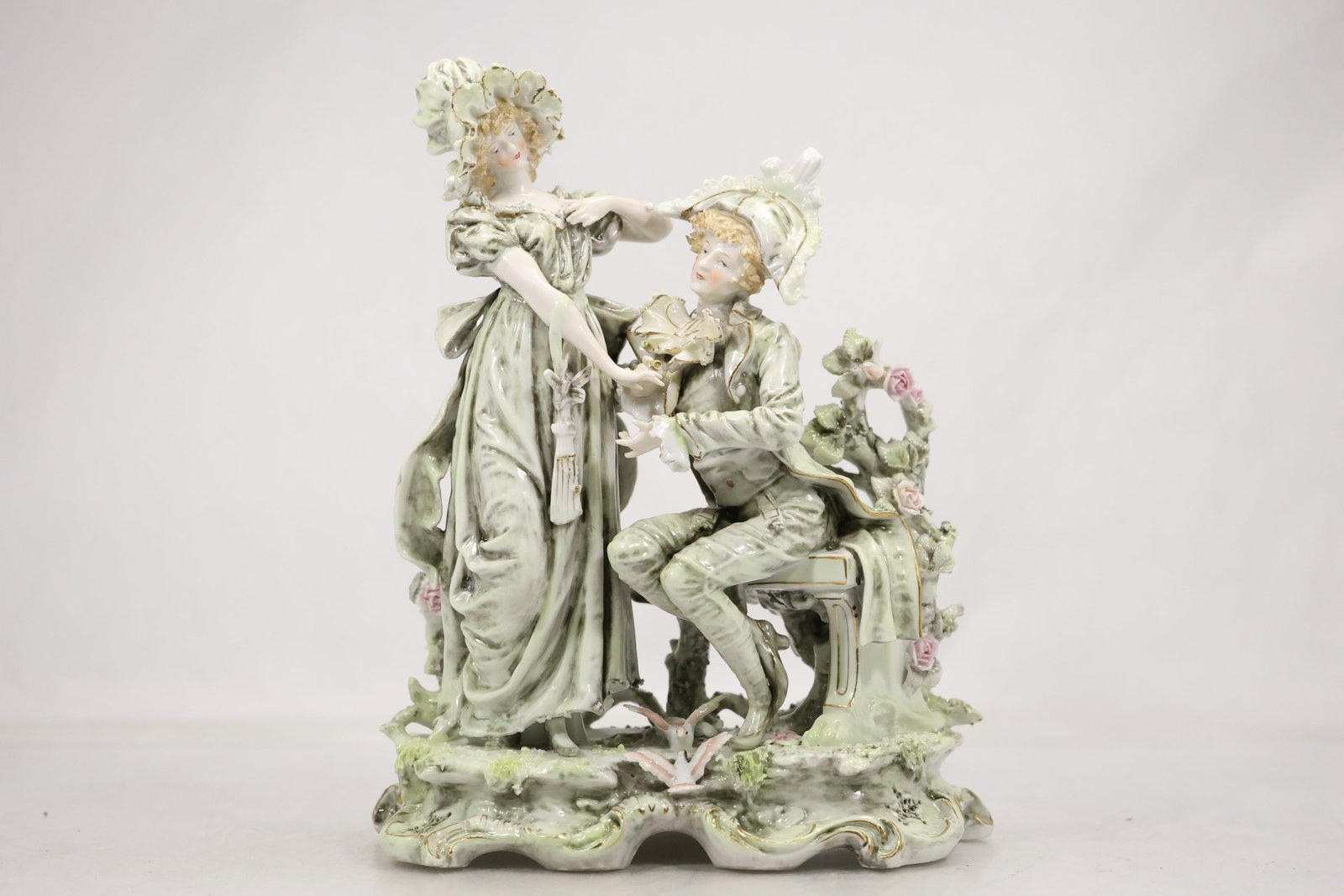 Green Glazed Porcelain Asian Figural Group: A green glazed porcelain figural group depicts multiple Asian figures modeled together on an integral base. The monochrome glaze detailed robes and grouped composition are visible in the photographs a