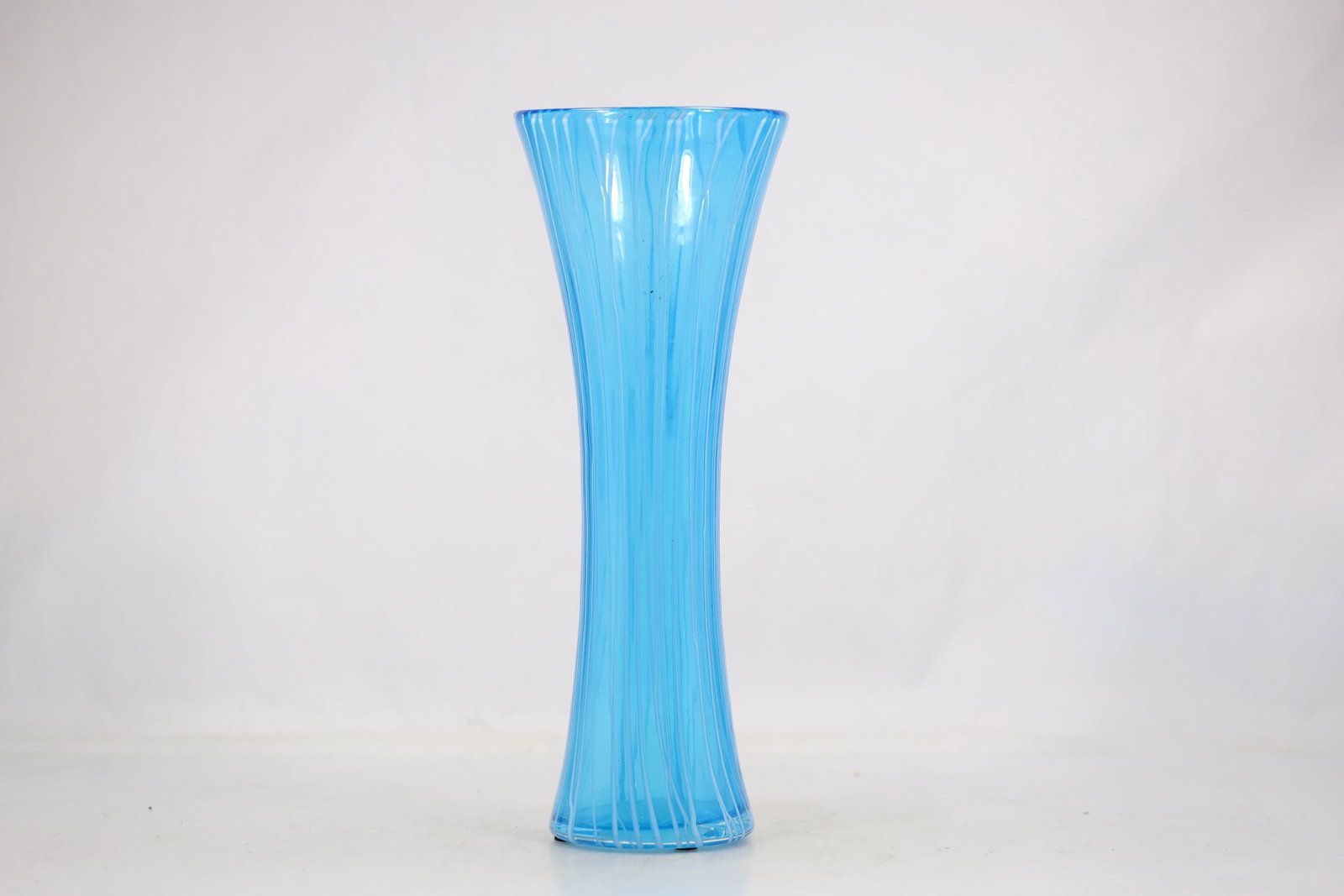 Tall Aqua Ribbed Art Glass Vase: A tall aqua blue art glass vase has a slender tapered body with pronounced vertical ribs and a narrow opening. The translucent color and repeated molded texture emphasize its modern decorative