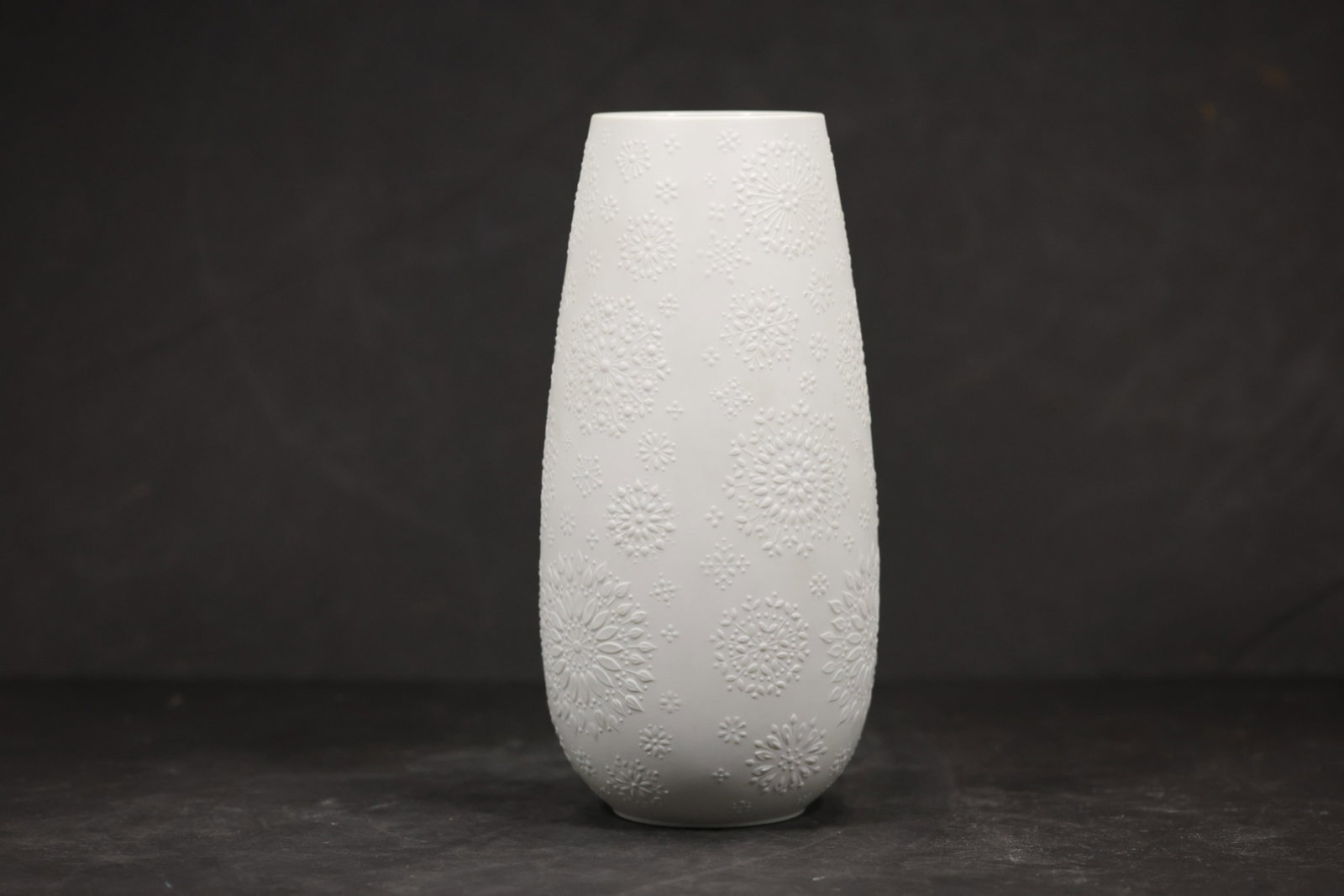 White Porcelain Modernist Vase with Green Mark: A white porcelain vase has an asymmetrical modernist profile with a narrow opening and smooth glazed surface. A green factory mark is visible on the underside but is not legible enough in the